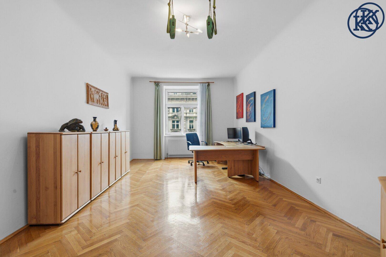 Helles Arbeitszimmer mit Fischgrätparkett, Holzschränken und Blick auf die Straße.