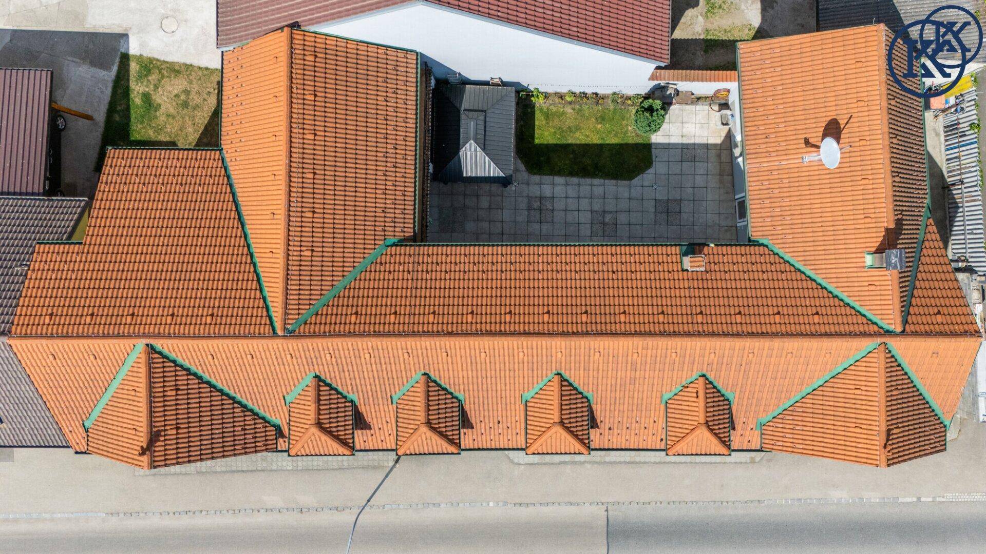 Vogelperspektive des Hauses mit detaillierter Ansicht des Ziegeldachs und des gepflasterten Innenhofs.