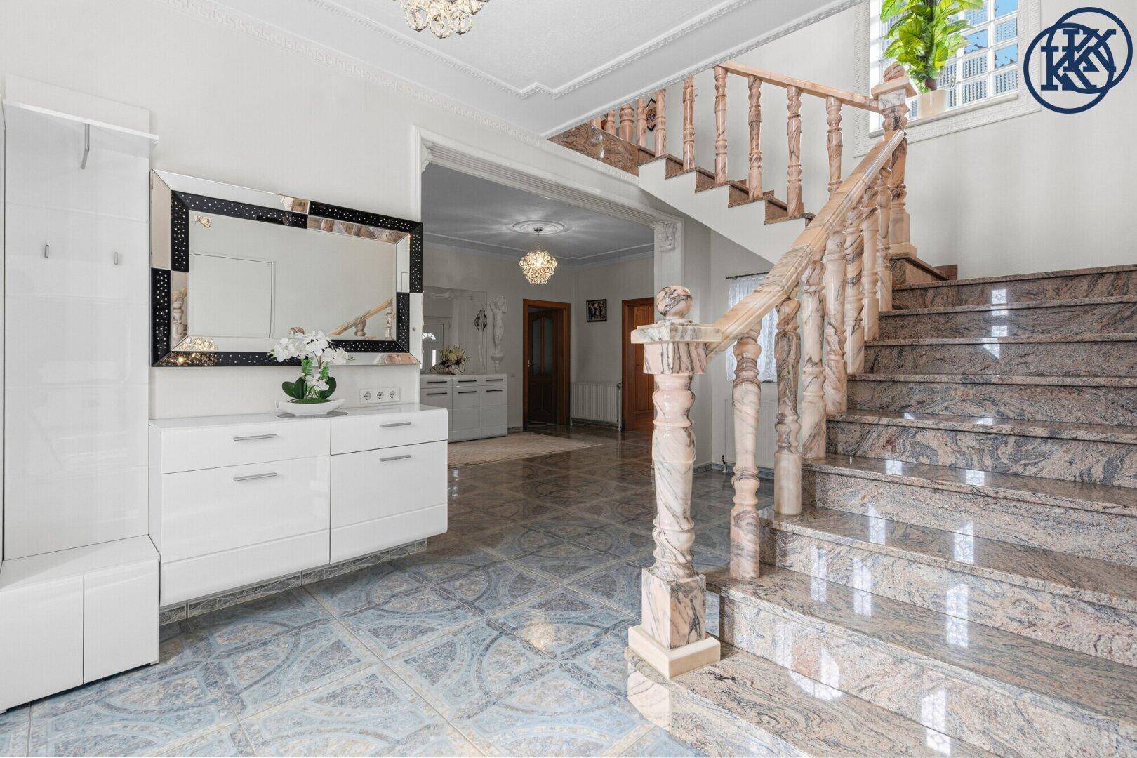Heller Eingangsbereich mit eleganter Granittreppe, gemusterten Fliesen und moderner Garderobe.