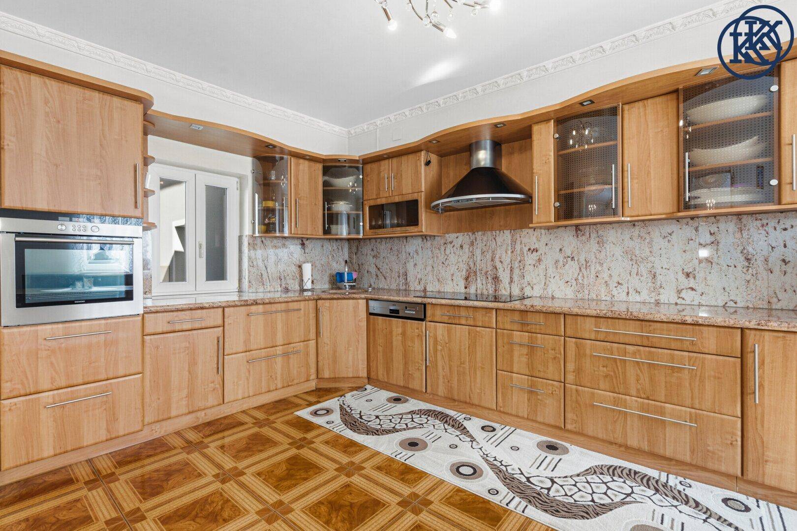 Funktionale Küche mit hellen Holzschränken, Granitarbeitsplatten und integrierten Geräten.
