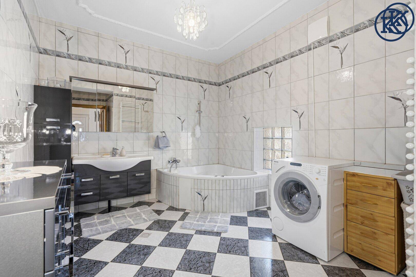 Geräumiges Badezimmer mit schwarz-weißem Fliesenboden, Eckbadewanne und Doppelwaschbecken.