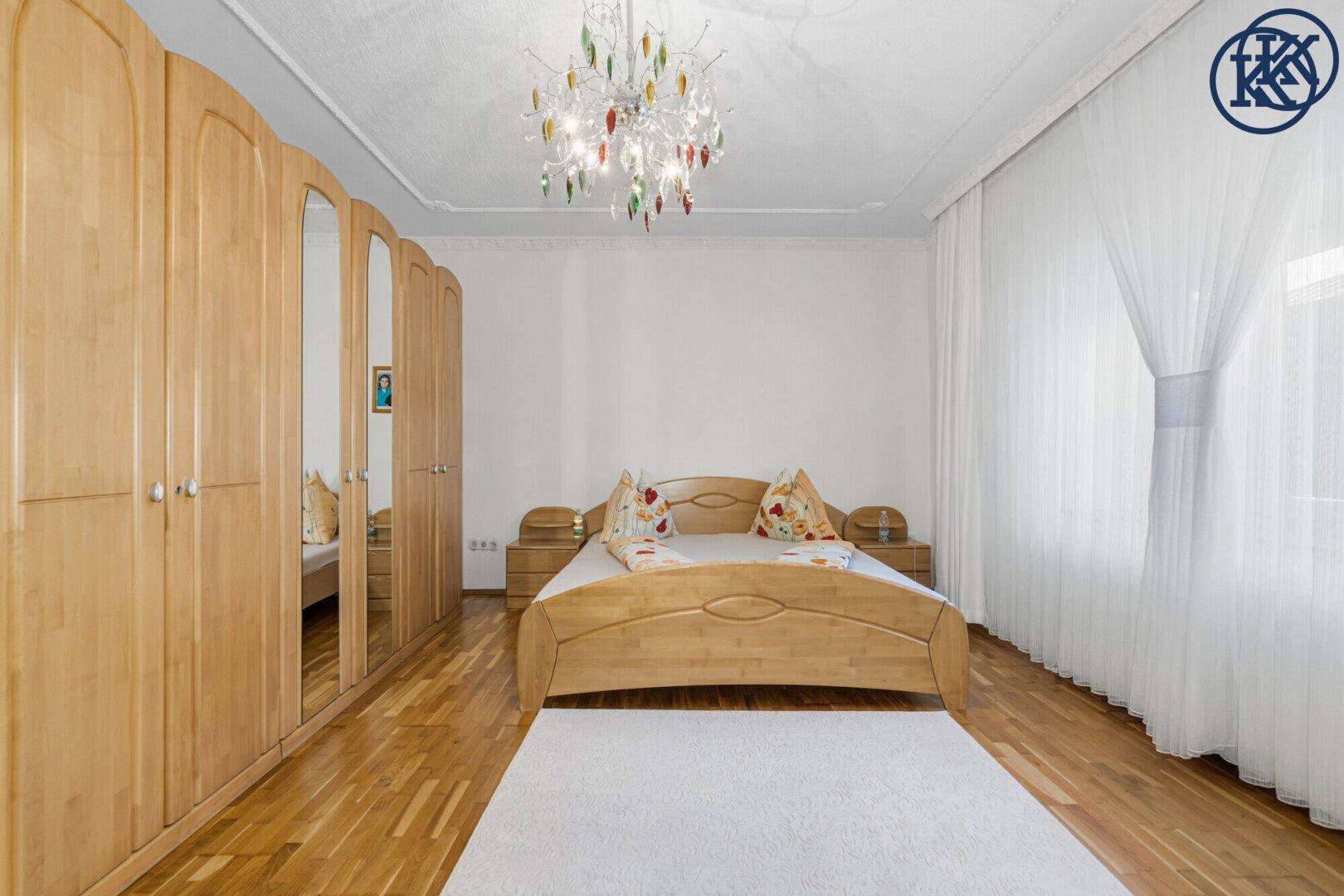 Helles Schlafzimmer mit Holzbett, Spiegelschränken und Parkettboden.
