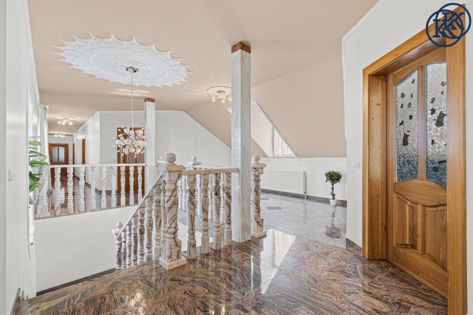 Geräumiger Flur im Obergeschoss mit eleganter Treppe und glänzendem Granitboden.