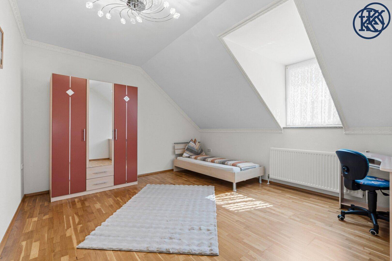 Helles Kinderzimmer mit Parkettboden, Einzelbett, Schreibtisch und Dachfenster.