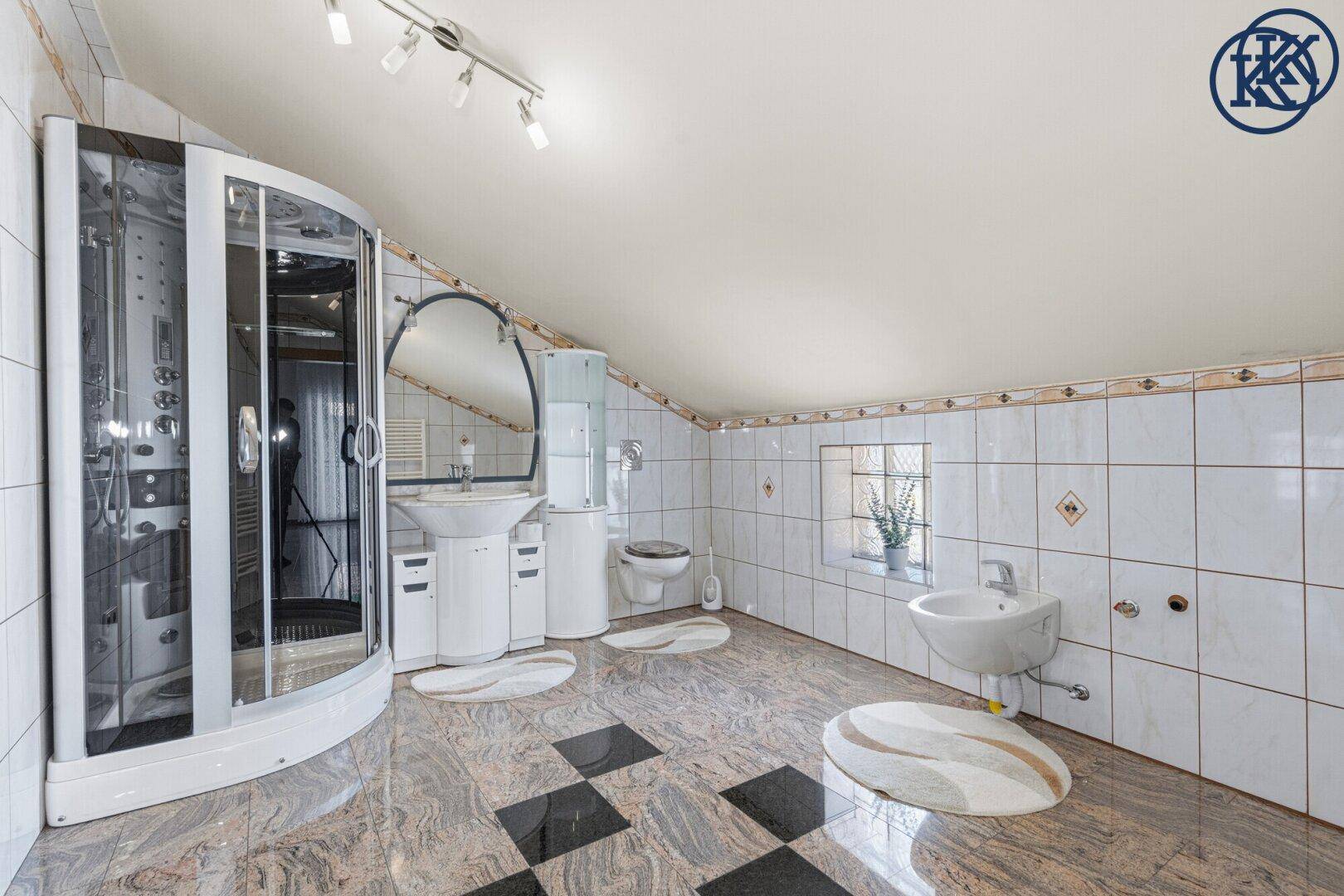Geräumiges Badezimmer im Dachgeschoss mit Granitboden, Duschkabine und Waschbecken.