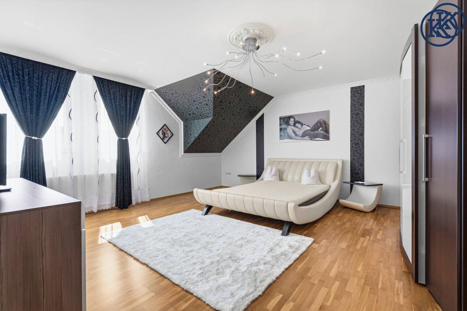 Modernes Schlafzimmer mit Parkettboden, Designerbett und dunkler Akzentwand im Dachgeschoss.