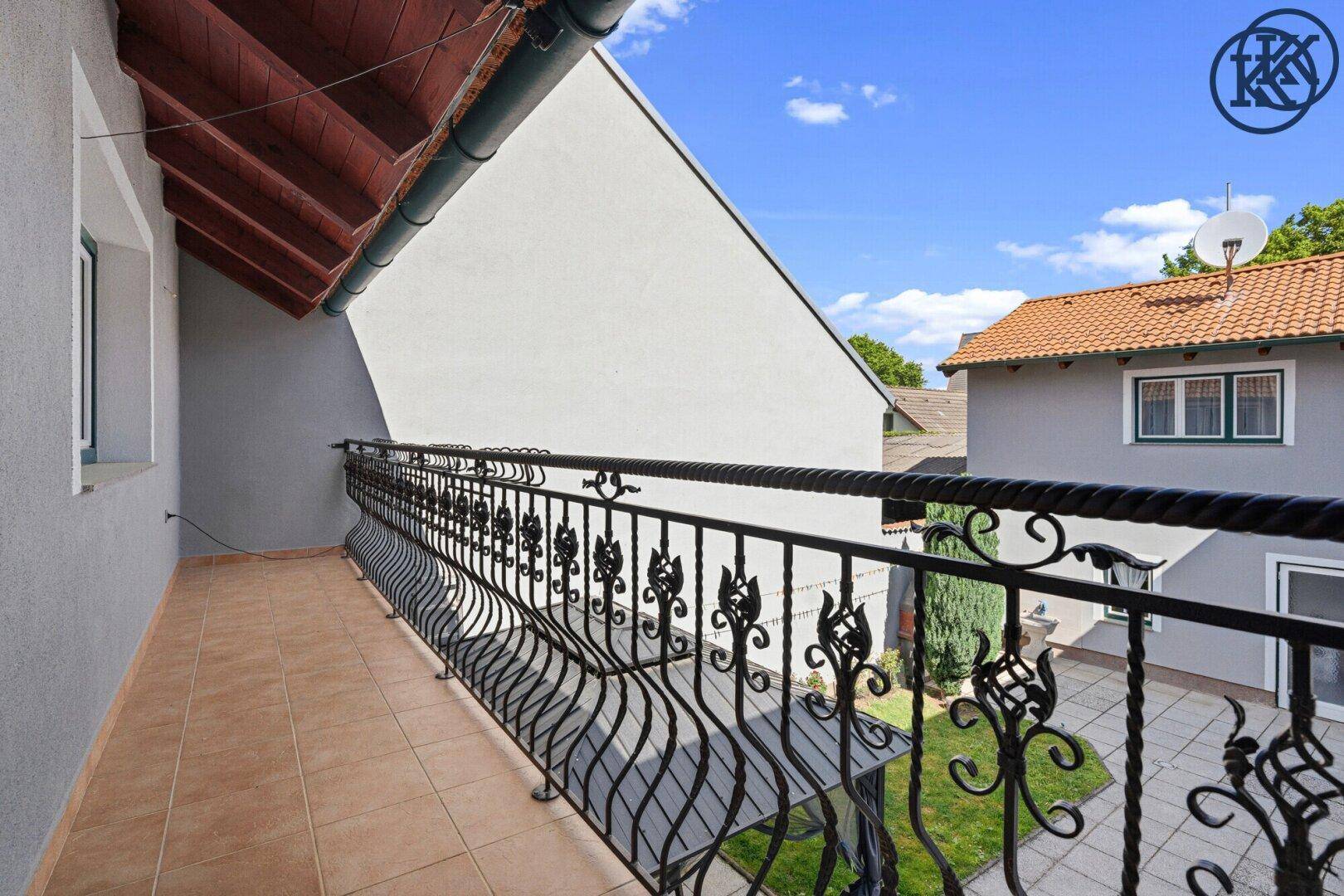 Großer Balkon mit schmiedeeisernem Geländer und Blick auf den Innenhof.