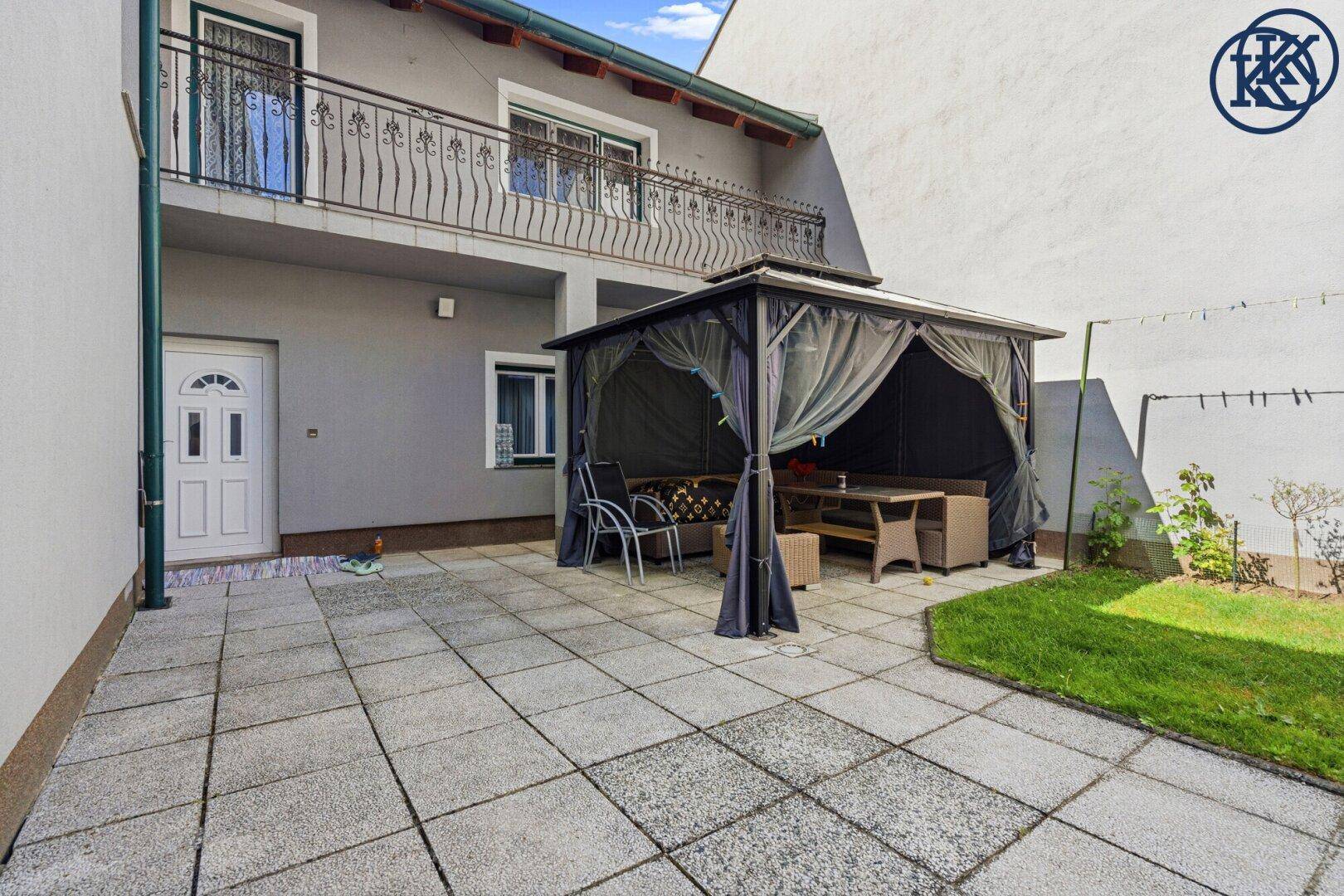 Gemütliche Gartenlaube mit Sitzgelegenheiten auf der gepflasterten Terrasse, direkt am Haus gelegen.