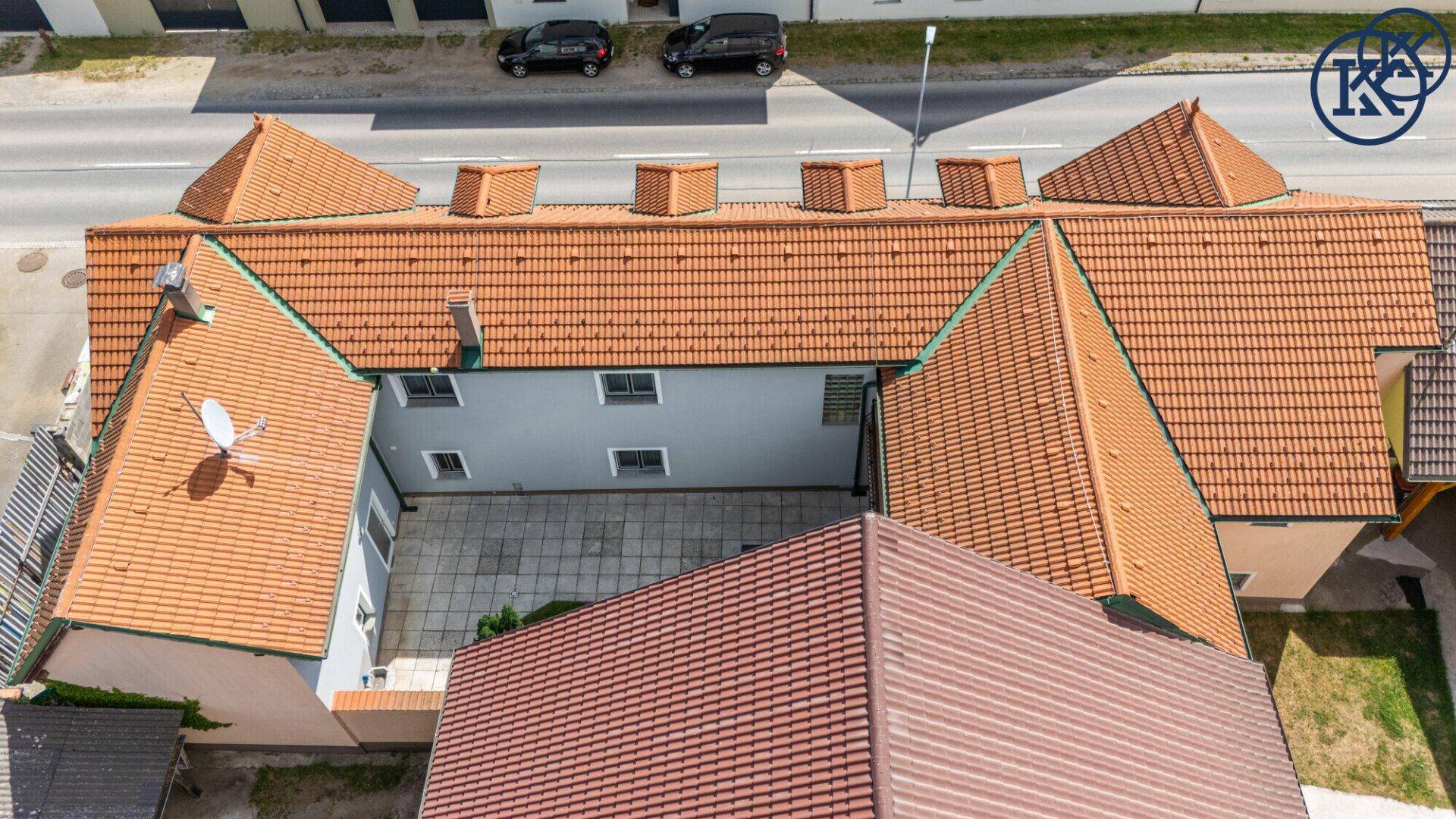 Luftaufnahme der Dachlandschaft mit Ziegeln und dem darunterliegenden Innenhofbereich.