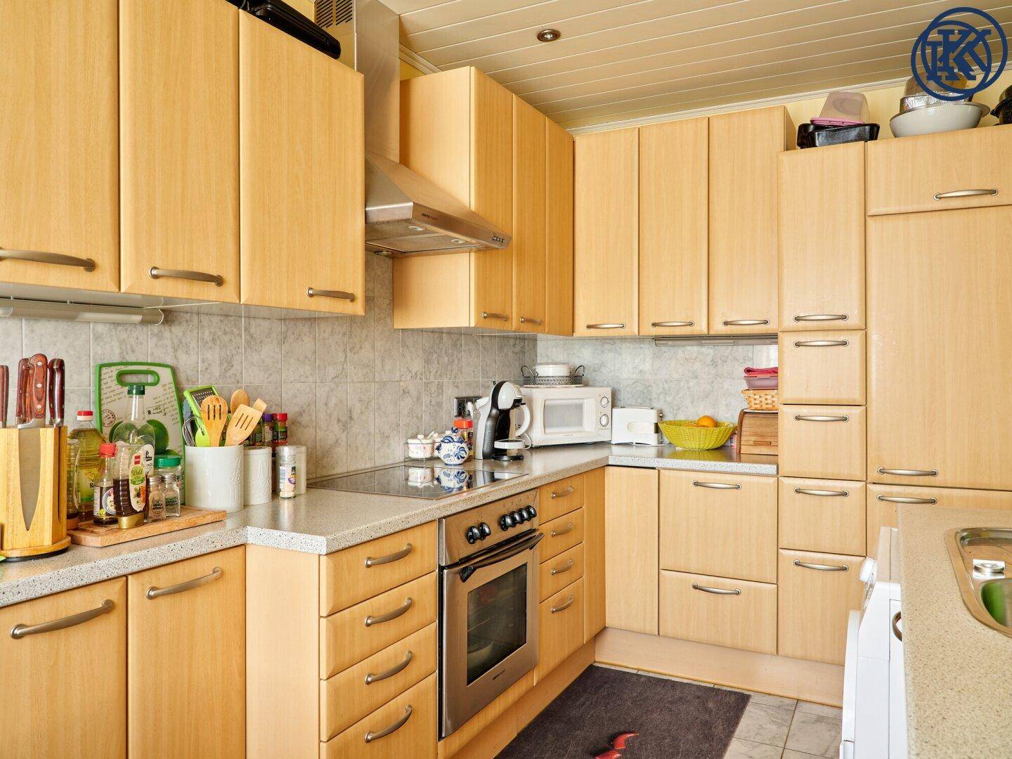 Gut ausgestattete Küche mit vielen Holzschränken, Backofen und Mikrowelle.