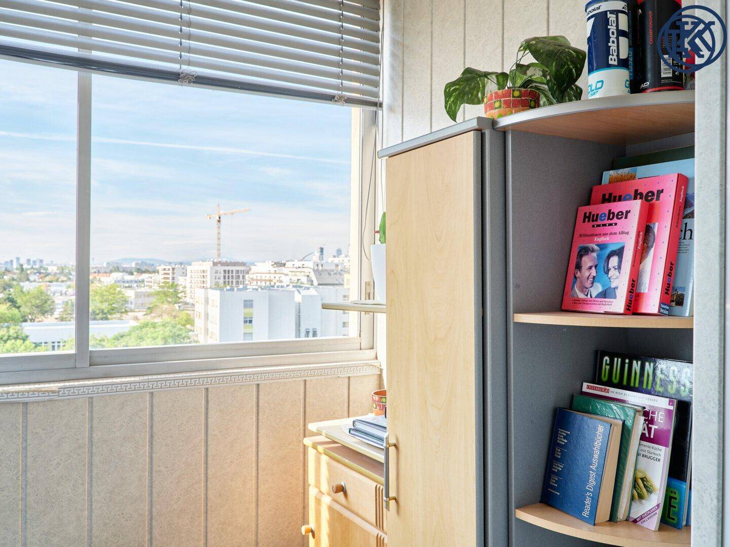 Gemütliche verglaste Loggia mit Stadtblick und Stauraum, ideal zum Entspannen und Lesen.