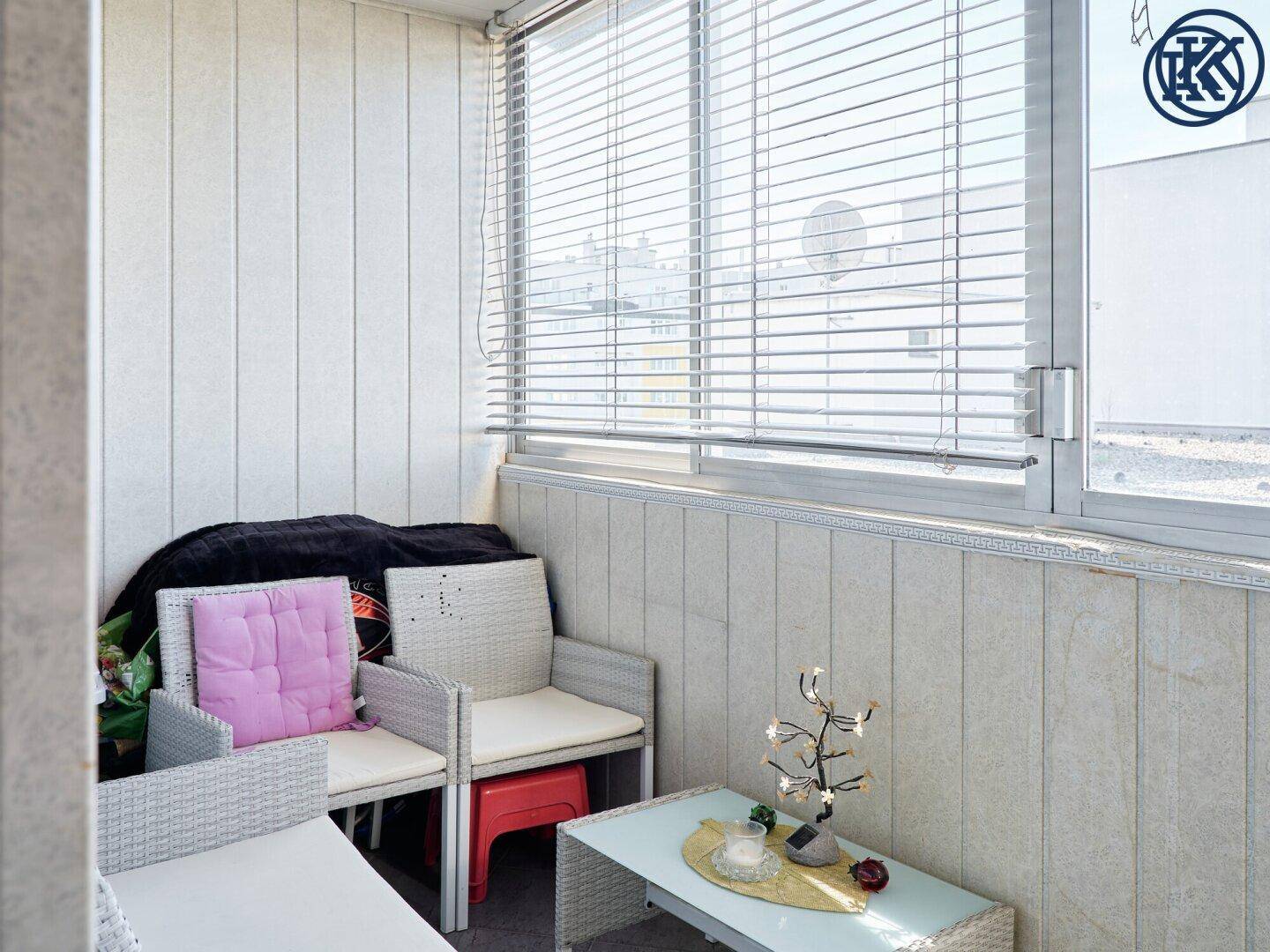 Helle Loggia mit bequemen Sitzgelegenheiten und Jalousien, perfekt für entspannte Stunden.