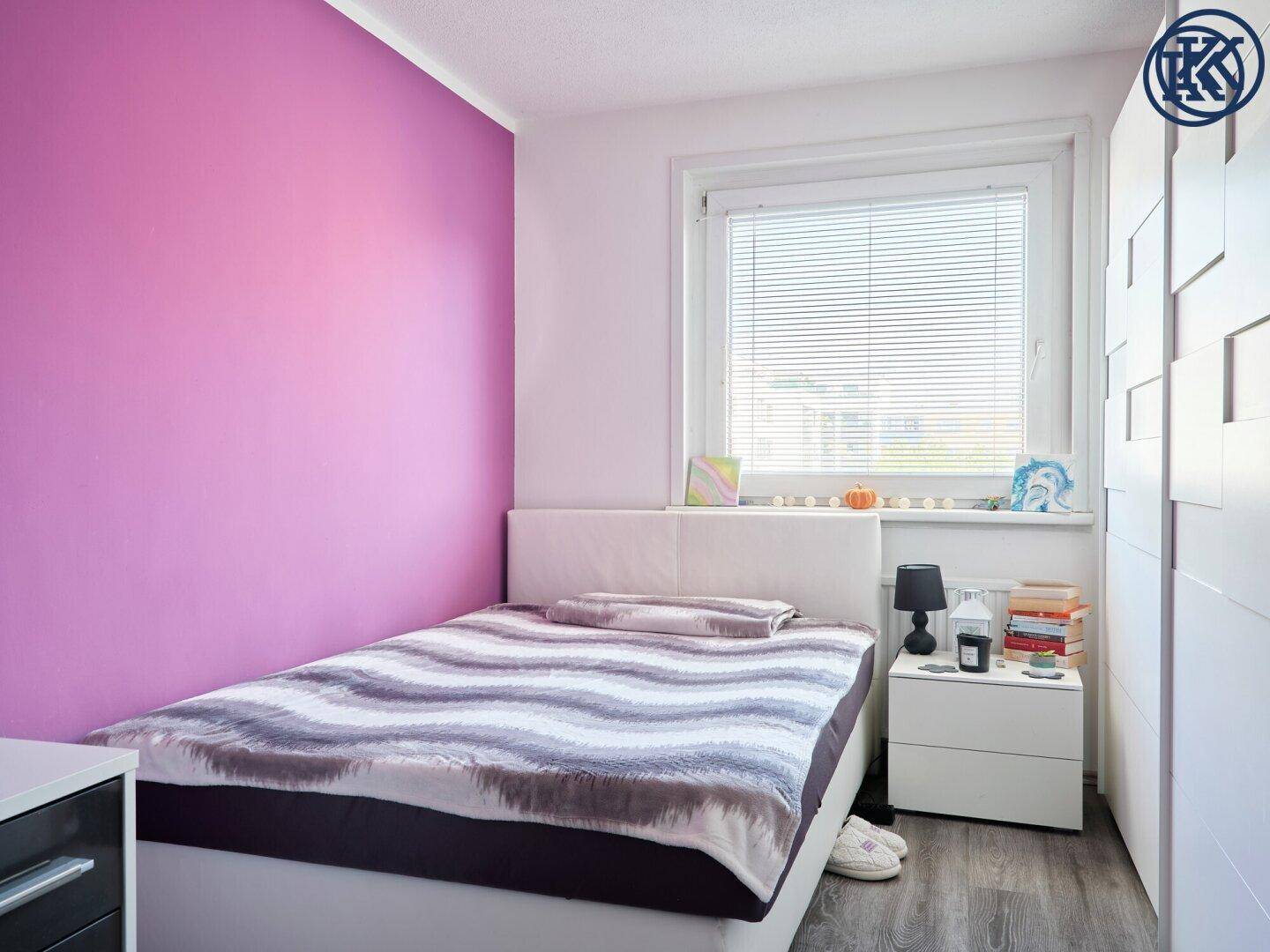Gemütliches Schlafzimmer mit Bett, Fenster und weißem Kleiderschrank, farbige Wand.
