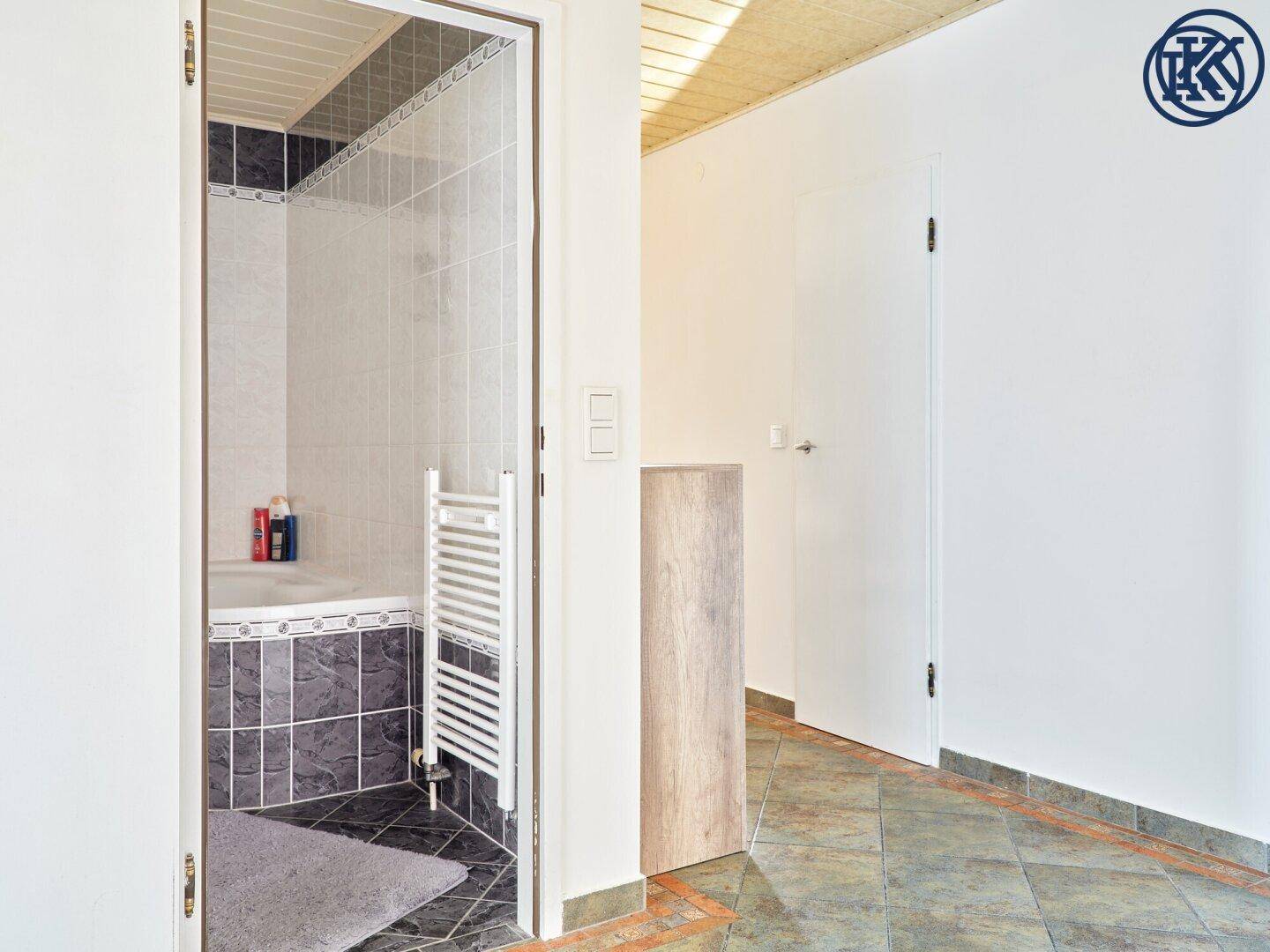 Heller Flur mit Zugang zum Badezimmer und weiteren Räumen, gefliester Boden.