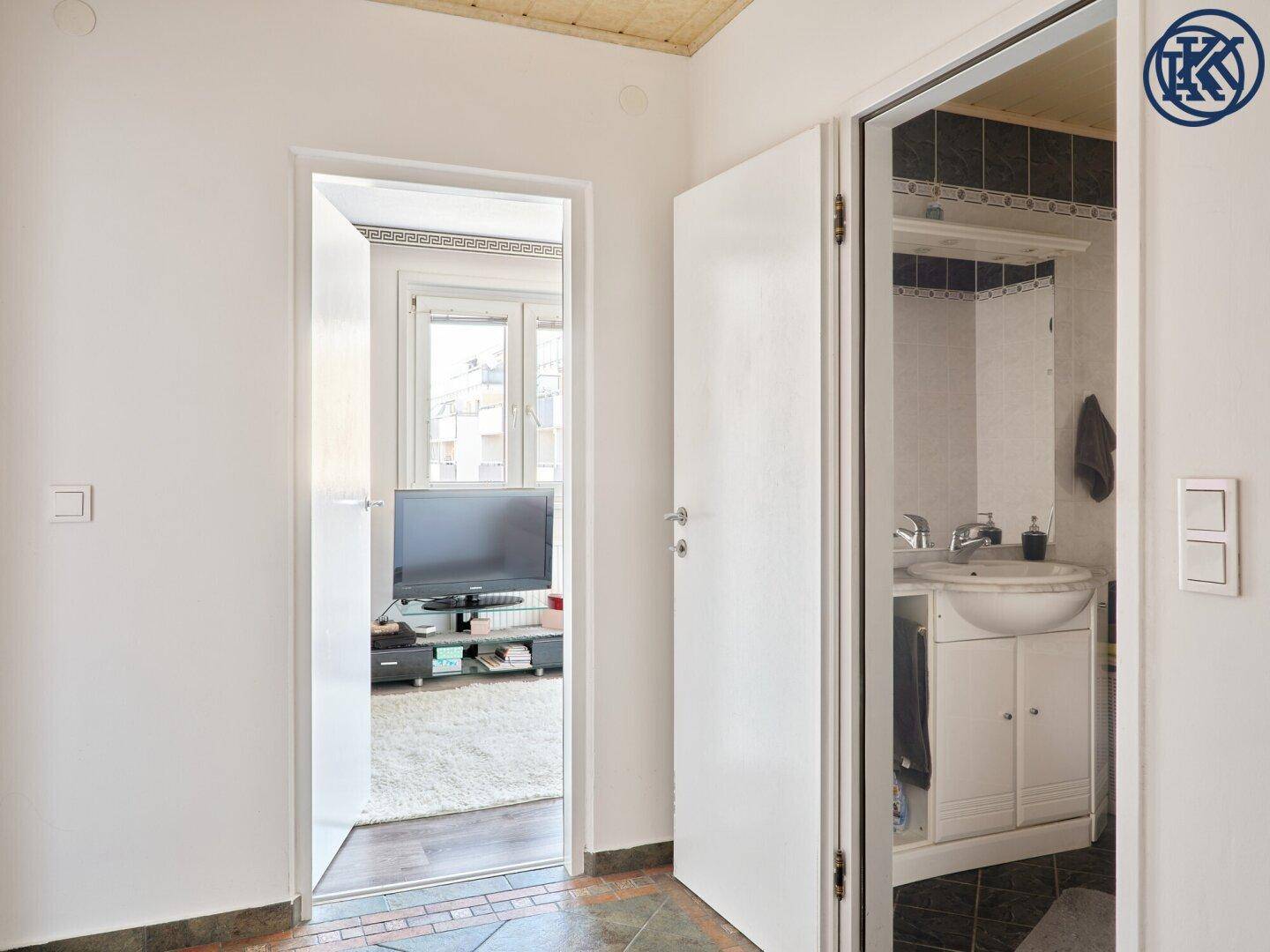 Flur mit Blick in das Wohnzimmer und das Badezimmer, gefliester Boden.