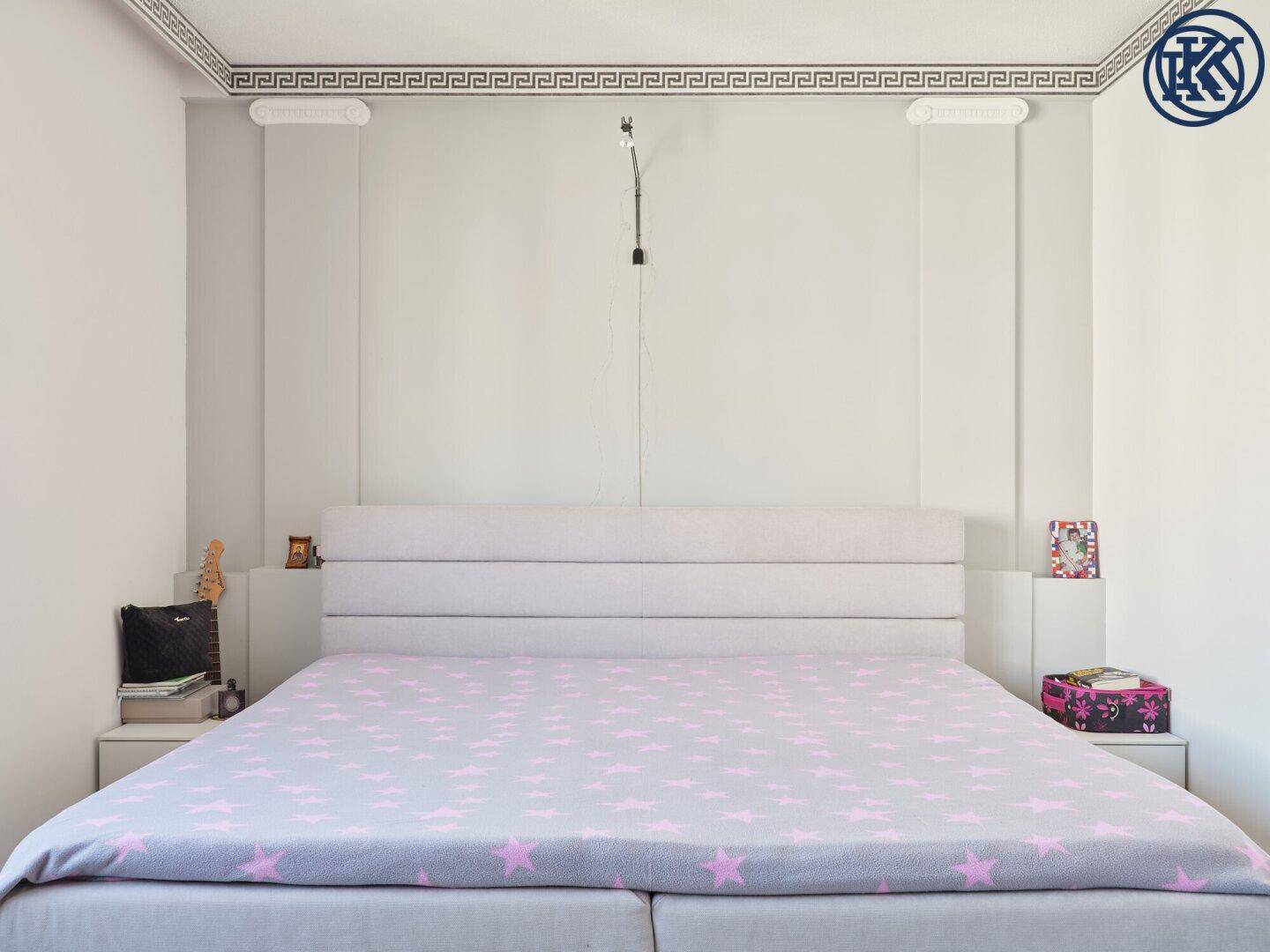 Schlafzimmer mit großem Doppelbett und eleganter Deckenverzierung.