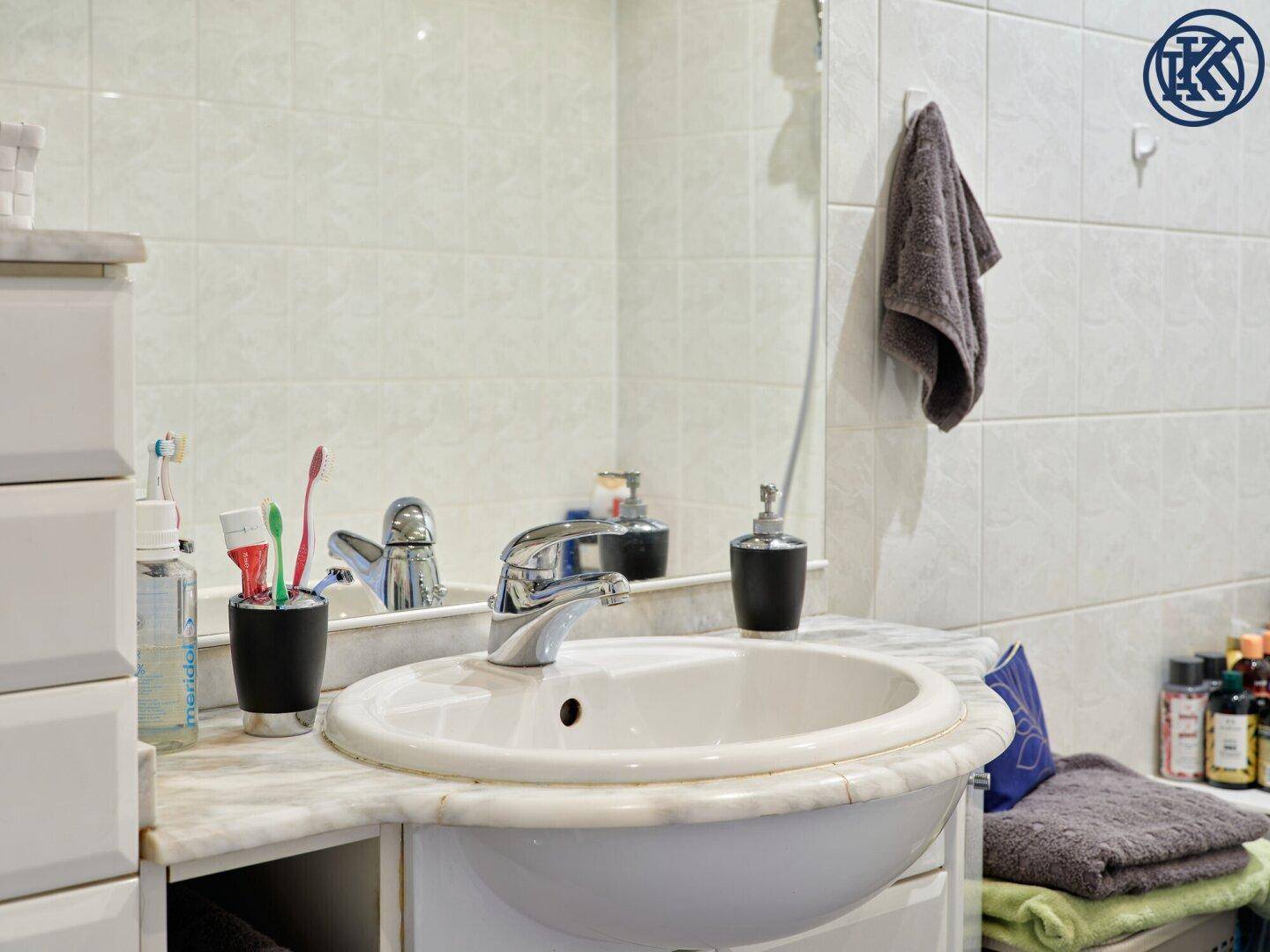 Detailaufnahme des Waschbeckens im Badezimmer mit Spiegel und Fliesen.
