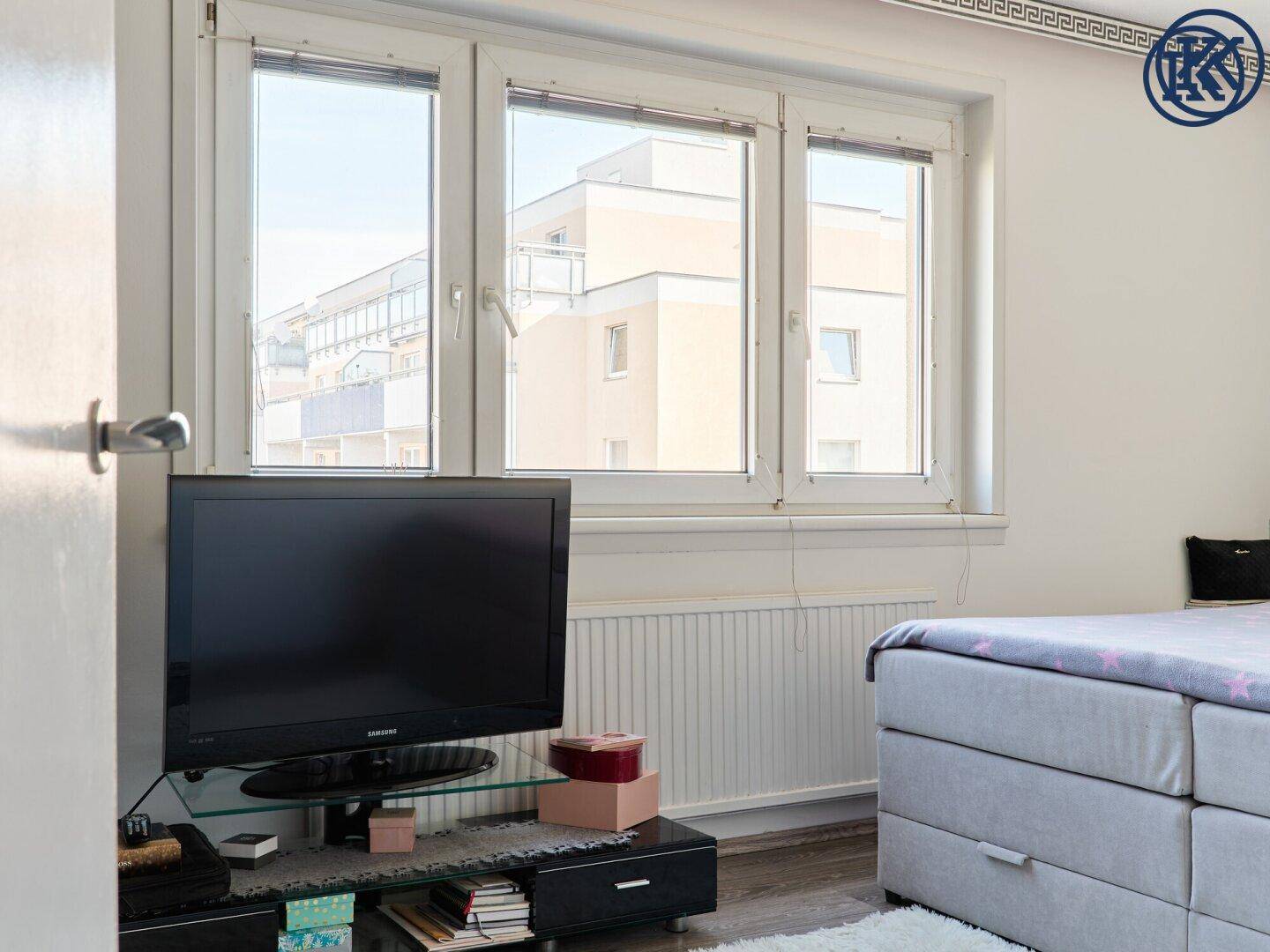 Helles Schlafzimmer mit Fernseher und weitem Blick aus den großen Fenstern.