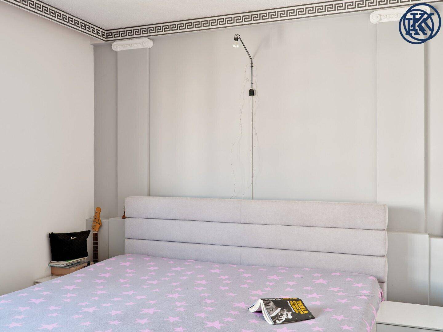 Geräumiges Schlafzimmer mit großem Bett und dekorativer Deckenleiste.
