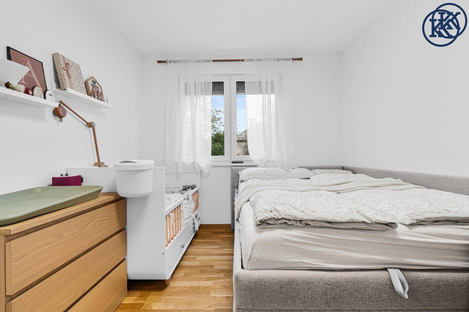 Freundliches Schlafzimmer mit Bett, Babybett und Holzkommode, ideal für Familien.