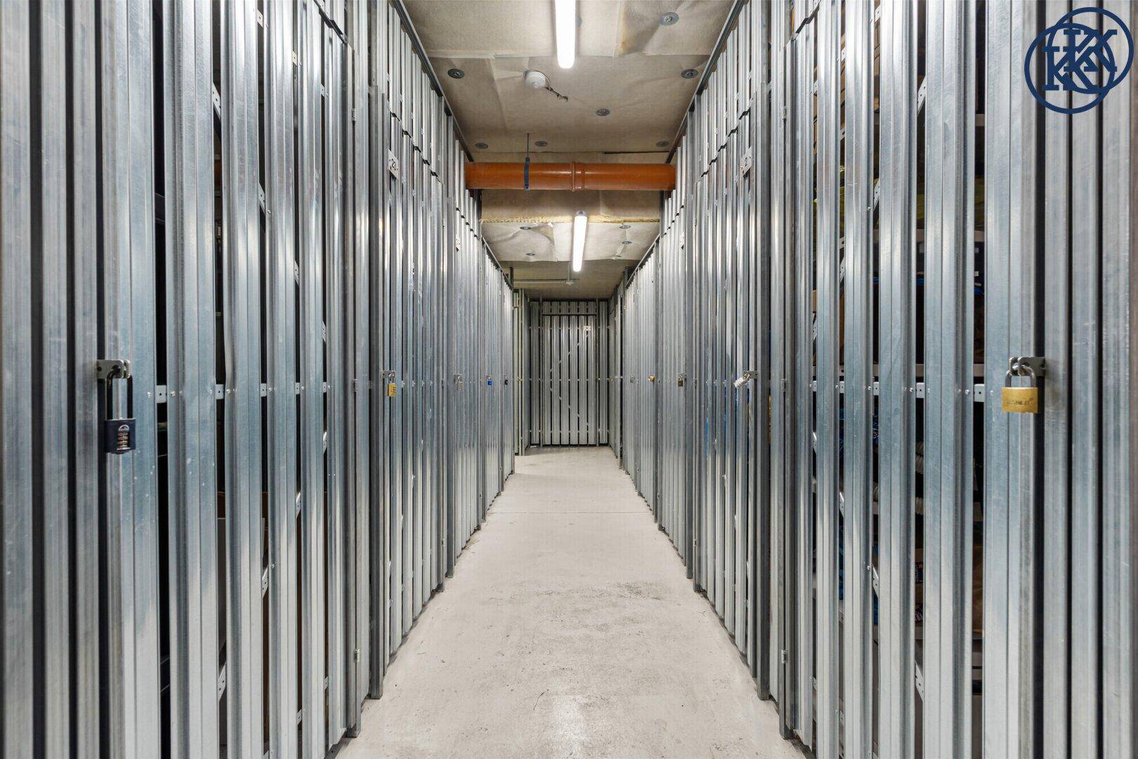 Langer Gang im Keller mit vielen individuellen Abstellboxen für Mieter.