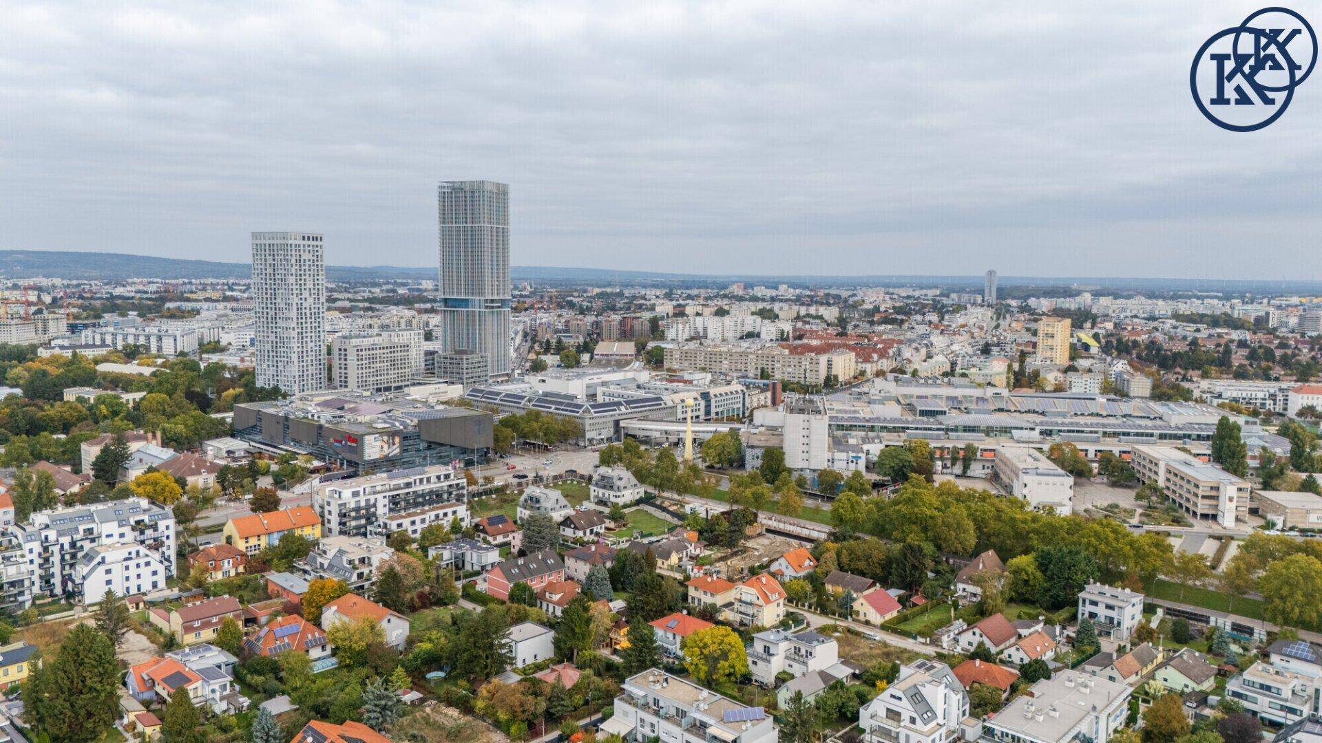 Weitläufiger Blick über städtische Bebauung mit Hochhäusern und grünen Vorstadtbereichen.