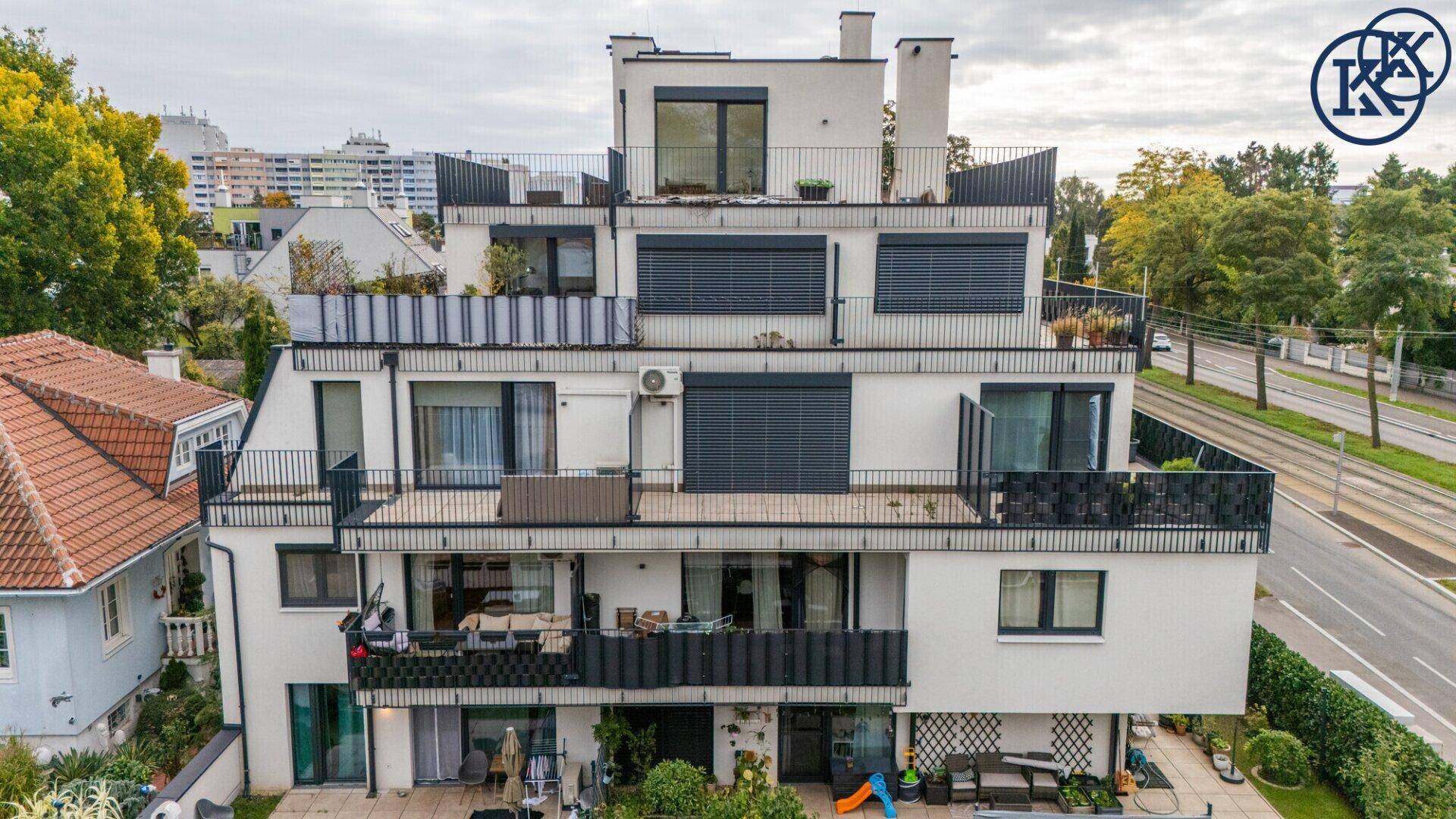 Moderne Wohnanlage von hinten mit mehreren Terrassen, Balkonen und begrünten Außenbereichen.