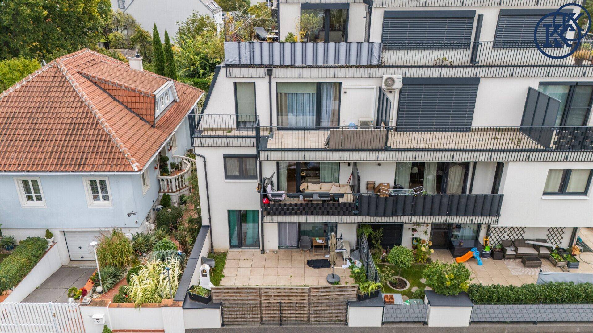 Rückansicht eines modernen Wohnhauses mit Terrassen, Balkonen und einem kleinen Gartenbereich.