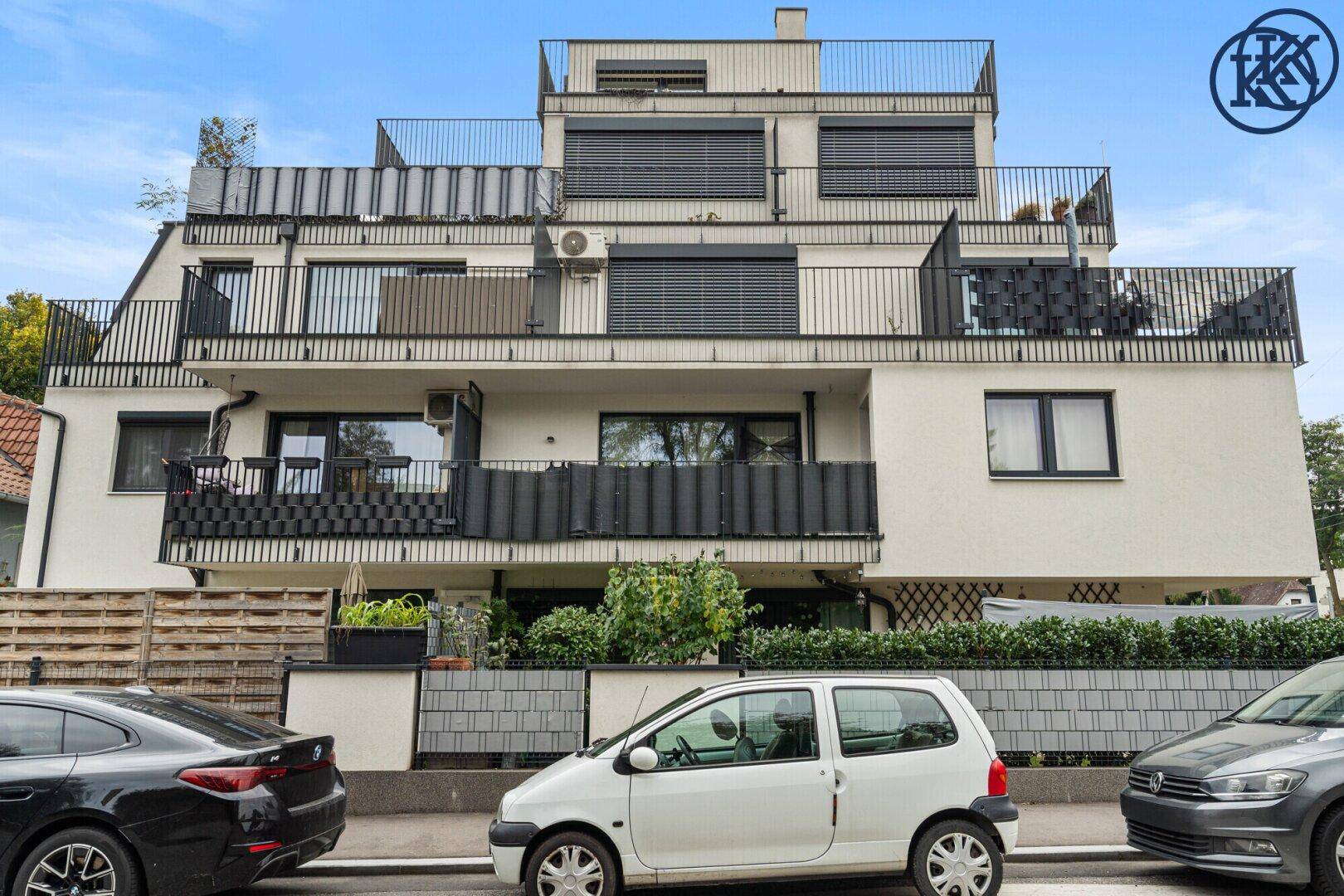 Moderne Wohnhausfassade mit Balkonen und großen Fenstern von der Straße aus gesehen.