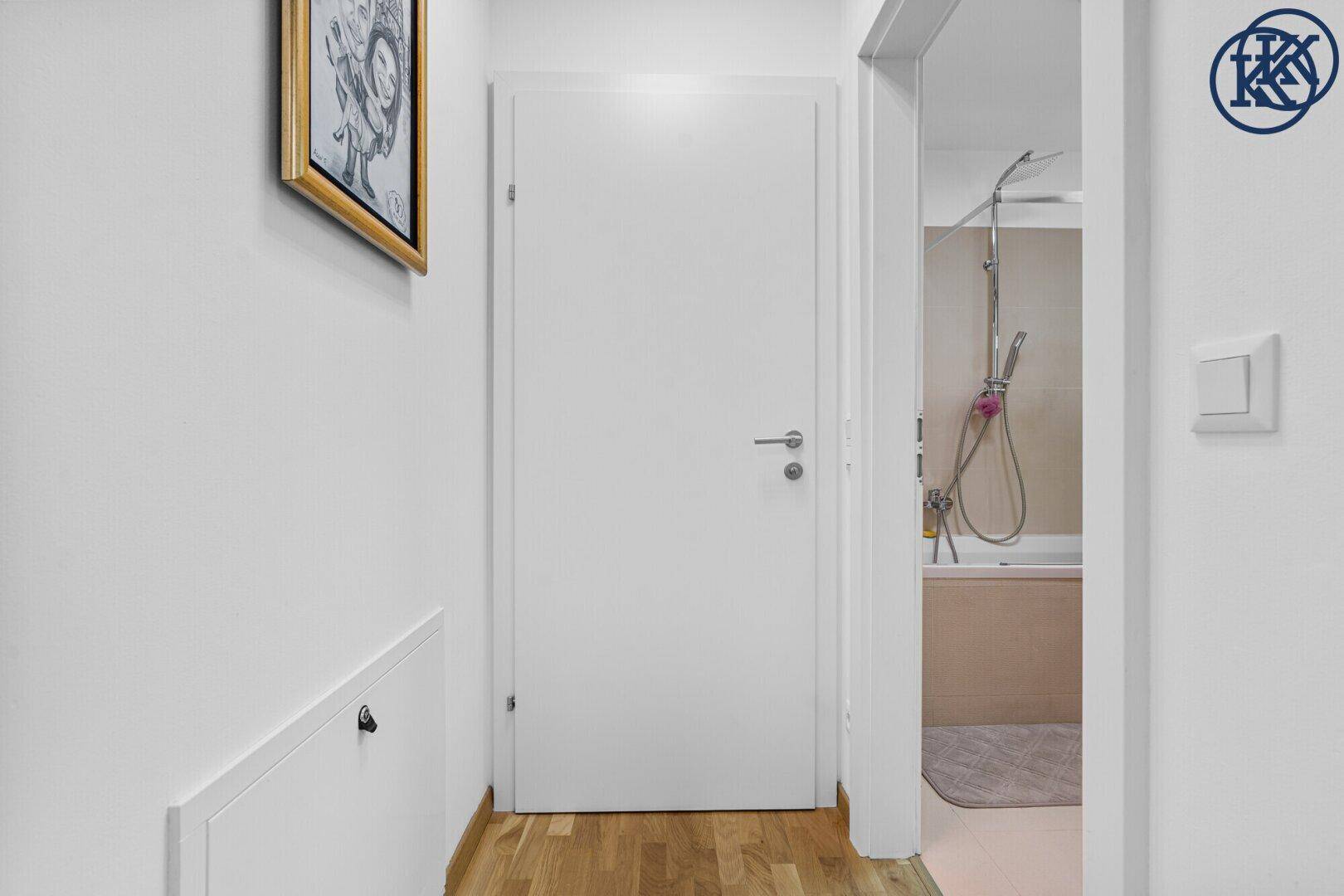 Heller Flur mit Holzboden, der zu einem modernen Badezimmer führt.