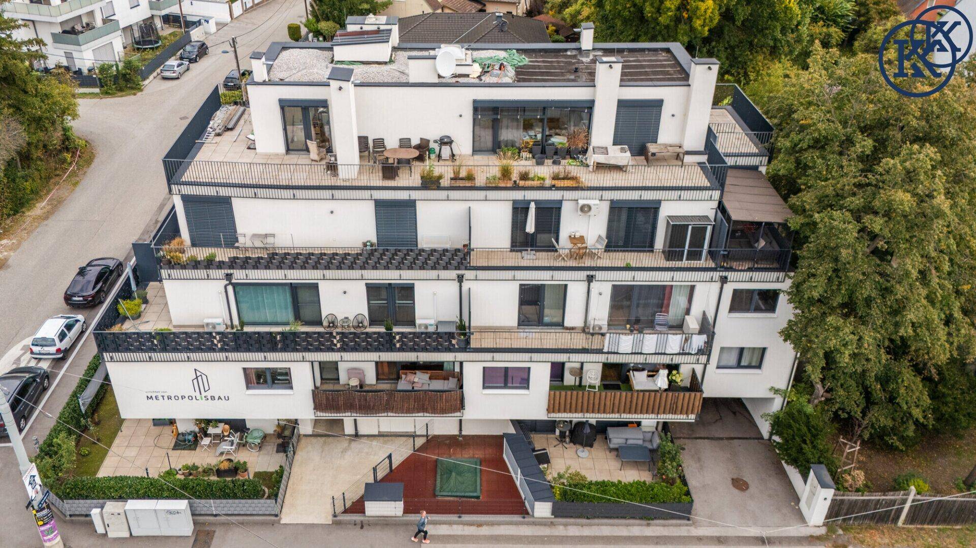 Luftaufnahme eines modernen Wohngebäudes mit mehreren Dachterrassen und Balkonen.