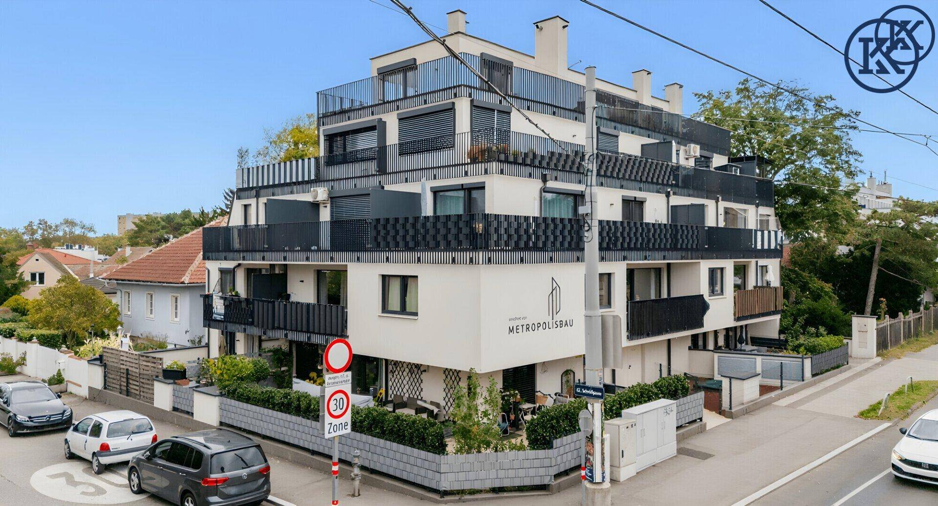 Modernes Eckgebäude mit Balkonen und großen Fenstern, umgeben von einer ruhigen Straße.