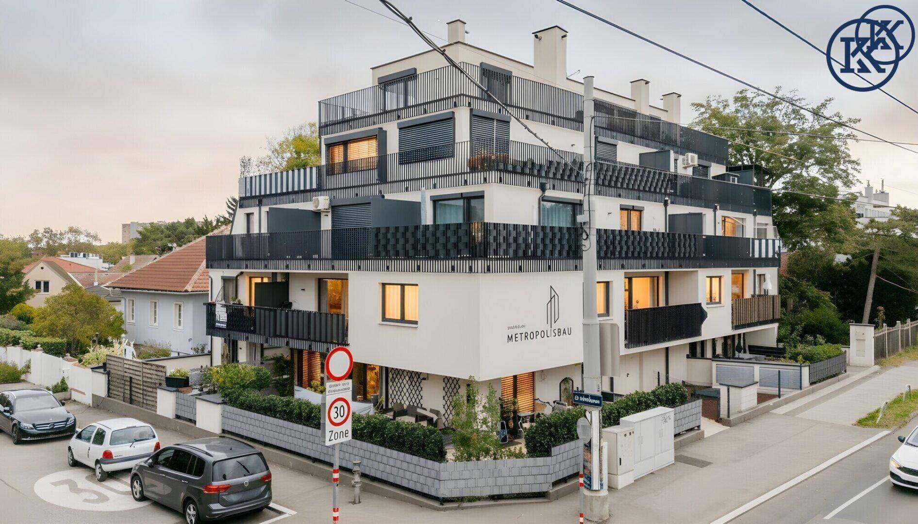 Modernes Eckgebäude in der Abenddämmerung mit beleuchteten Innenräumen und Balkonen.