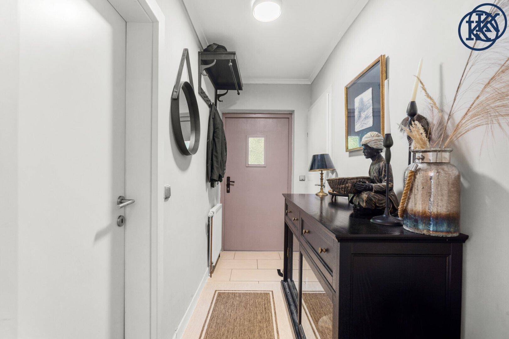 Heller Flur mit Fliesenboden, Garderobe und einer dekorativen Konsole mit Spiegel.