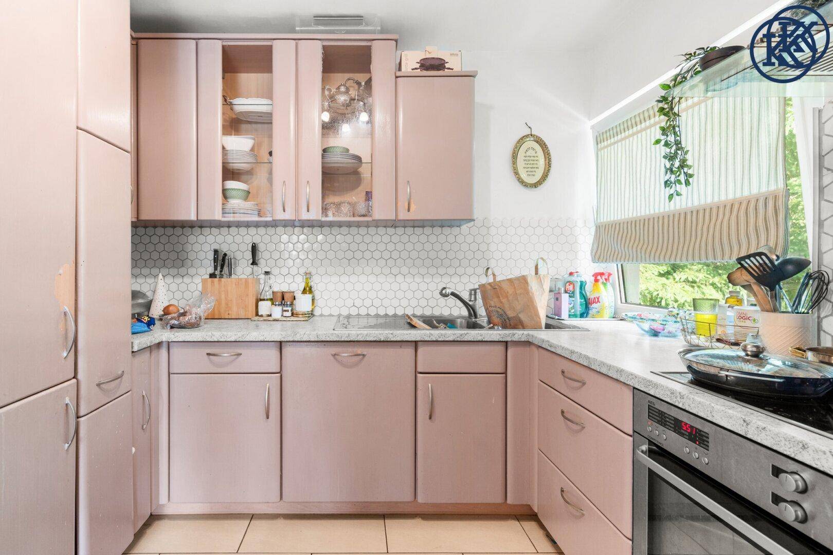 Funktionale Küche mit rosa Schränken, integriertem Backofen und sechseckigen Fliesen als Spritzschutz.
