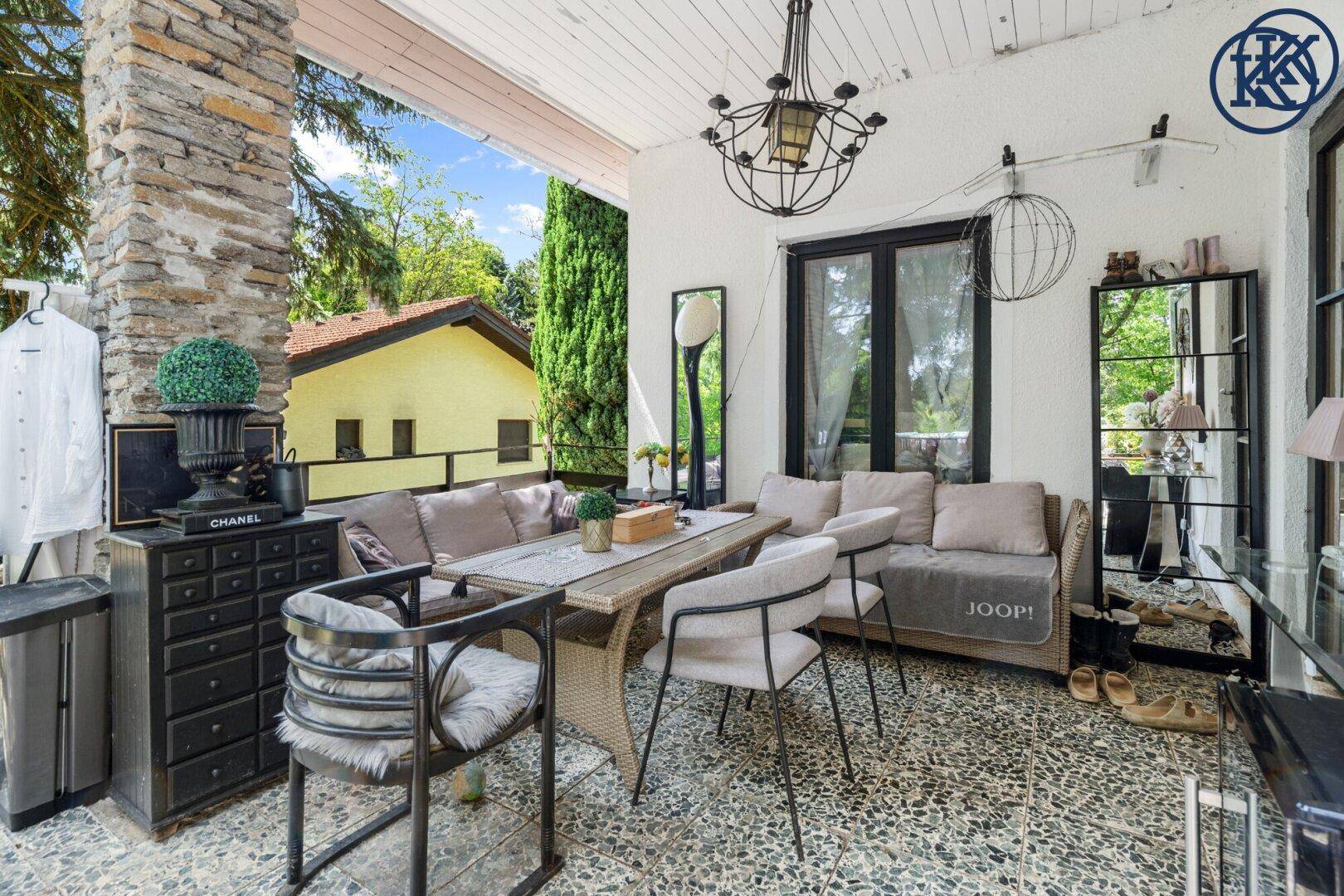 Überdachte Terrasse mit gemütlichen Gartenmöbeln und einem Esstisch für entspannte Stunden im Freien.