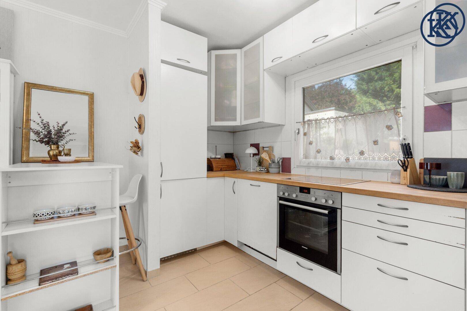 Moderne weiße Küche mit viel Stauraum und hellem Fenster für ausreichend Tageslicht.