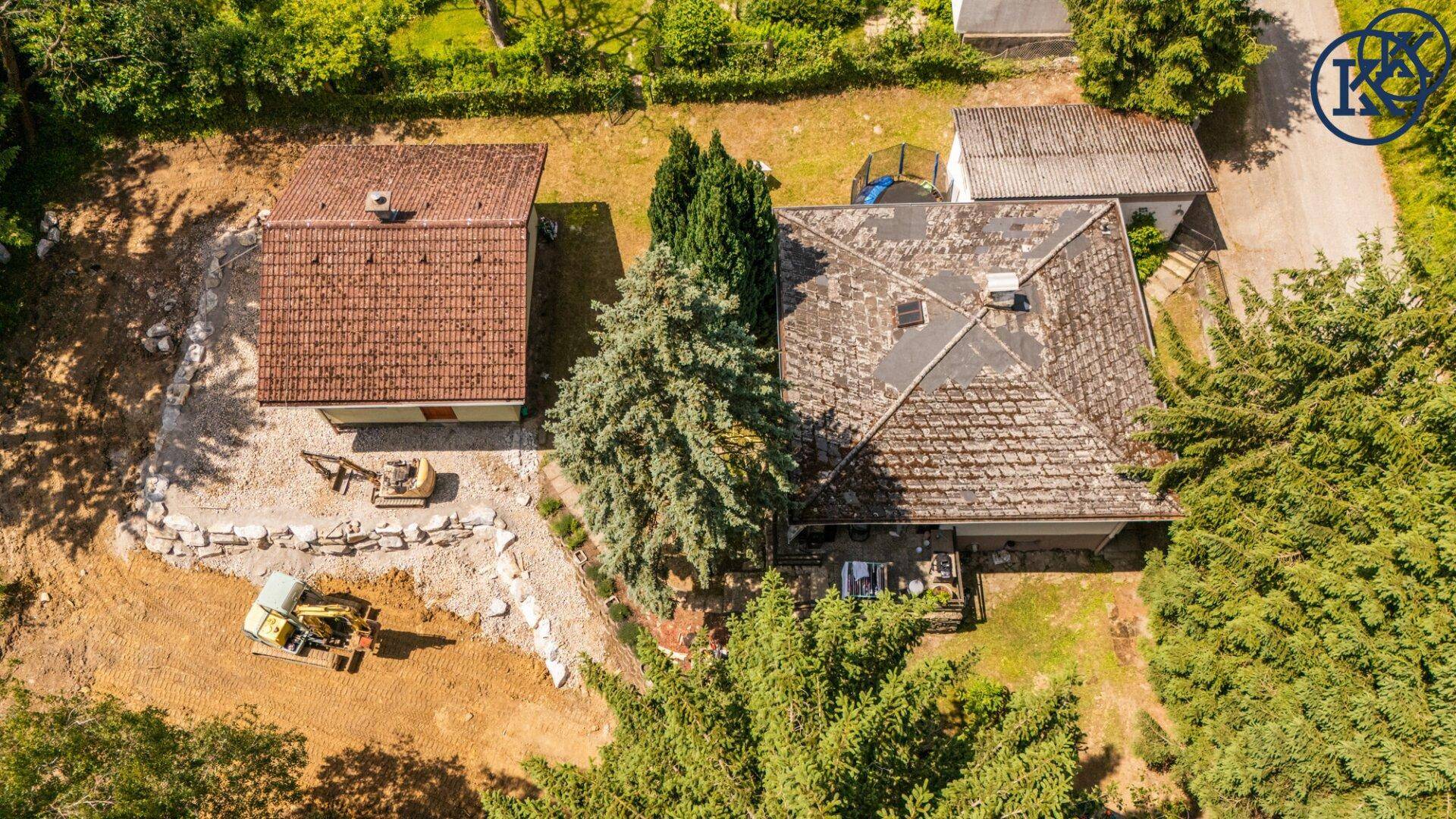 Luftaufnahme zweier Häuser mit umliegendem Grundstück und Baustellenbereich in ländlicher Umgebung.