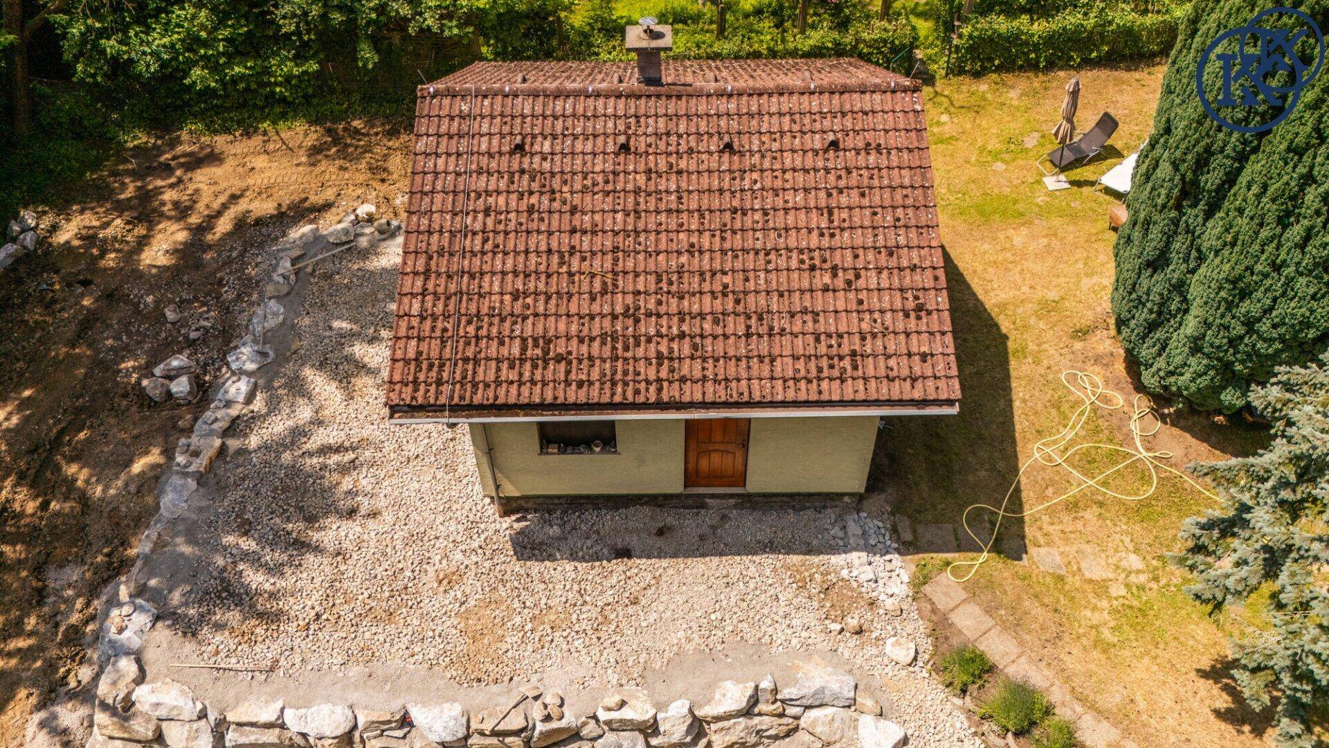 Nahaufnahme eines kleinen Hauses mit Ziegeldach und Kiesfläche im Bauzustand von oben.