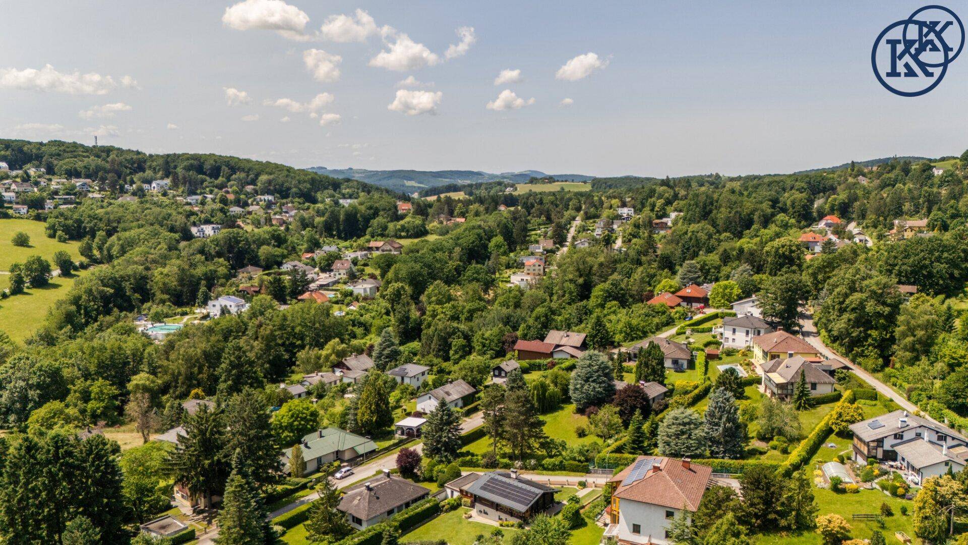Malerische Landschaftsaufnahme einer ländlichen Wohnsiedlung unter blauem Himmel mit Wolken.