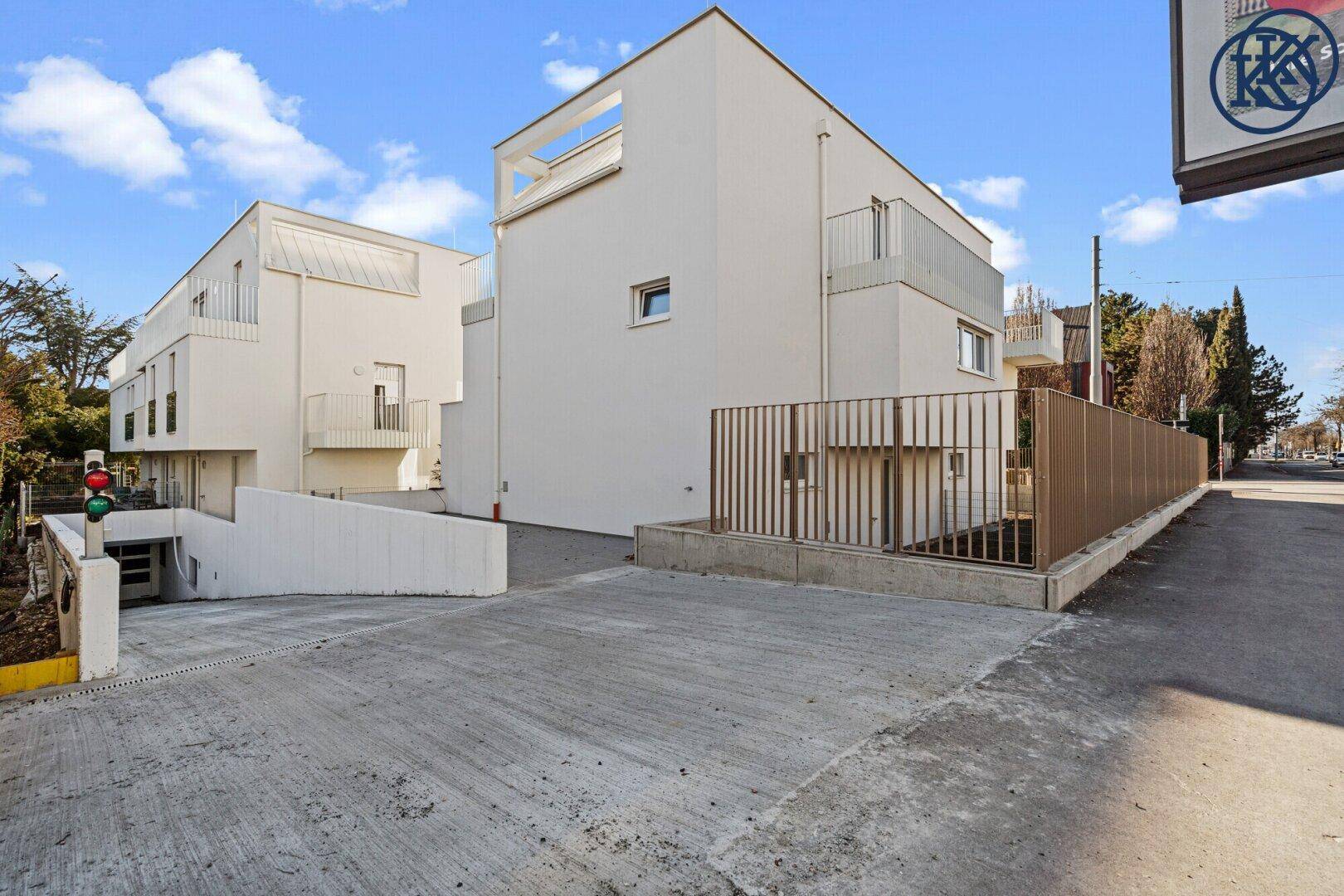 Moderne Wohngebäude mit Zufahrt zur Tiefgarage und minimalistischer Architektur.
