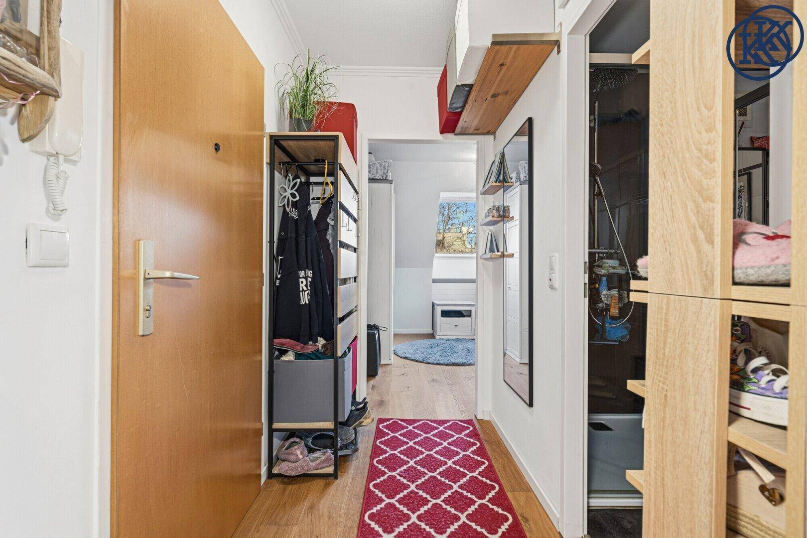 Heller Eingangsbereich mit Holzfußboden, praktischem Schuhregal und einem großen Spiegel.