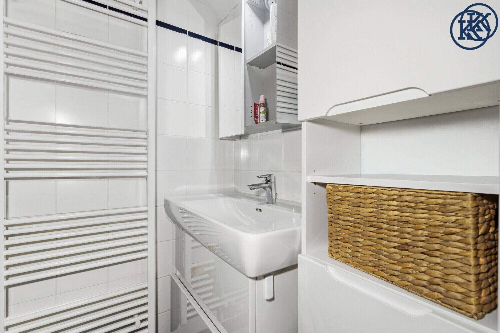 Helles Badezimmer mit modernem Waschbecken, Spiegelschrank und beheiztem Handtuchhalter.