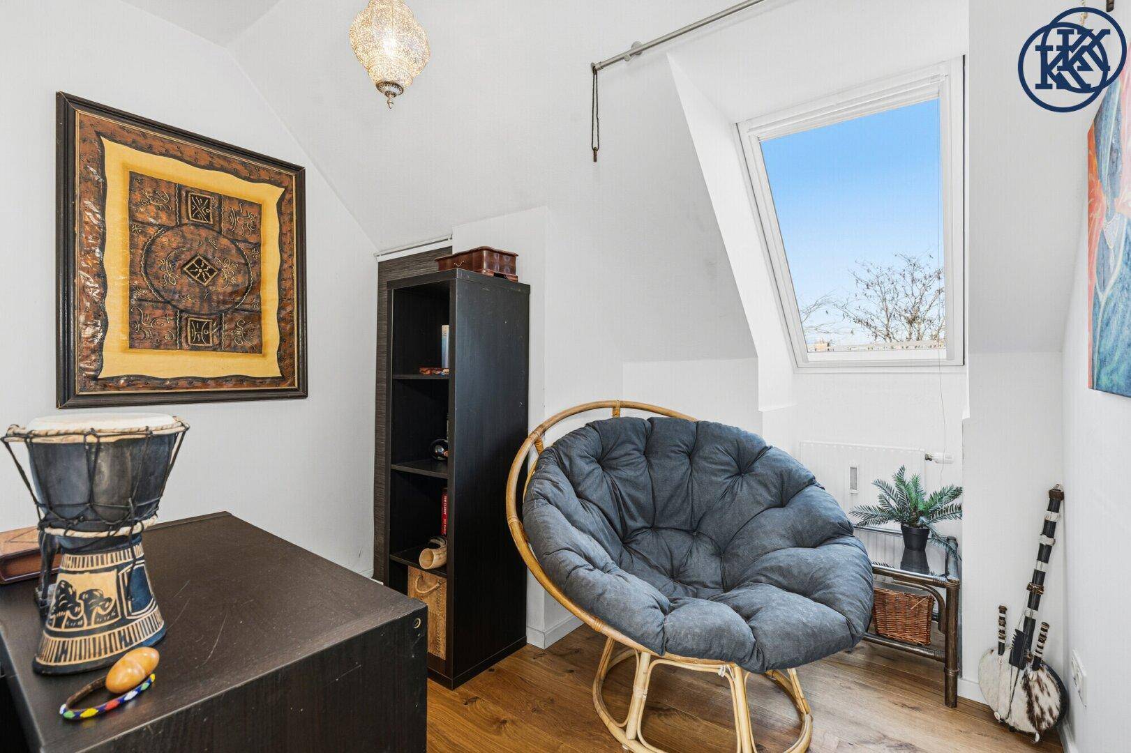Heller Arbeitsplatz mit Dachfenster, Bücherregal und dekorativen Elementen in einem ruhigen Bereich.