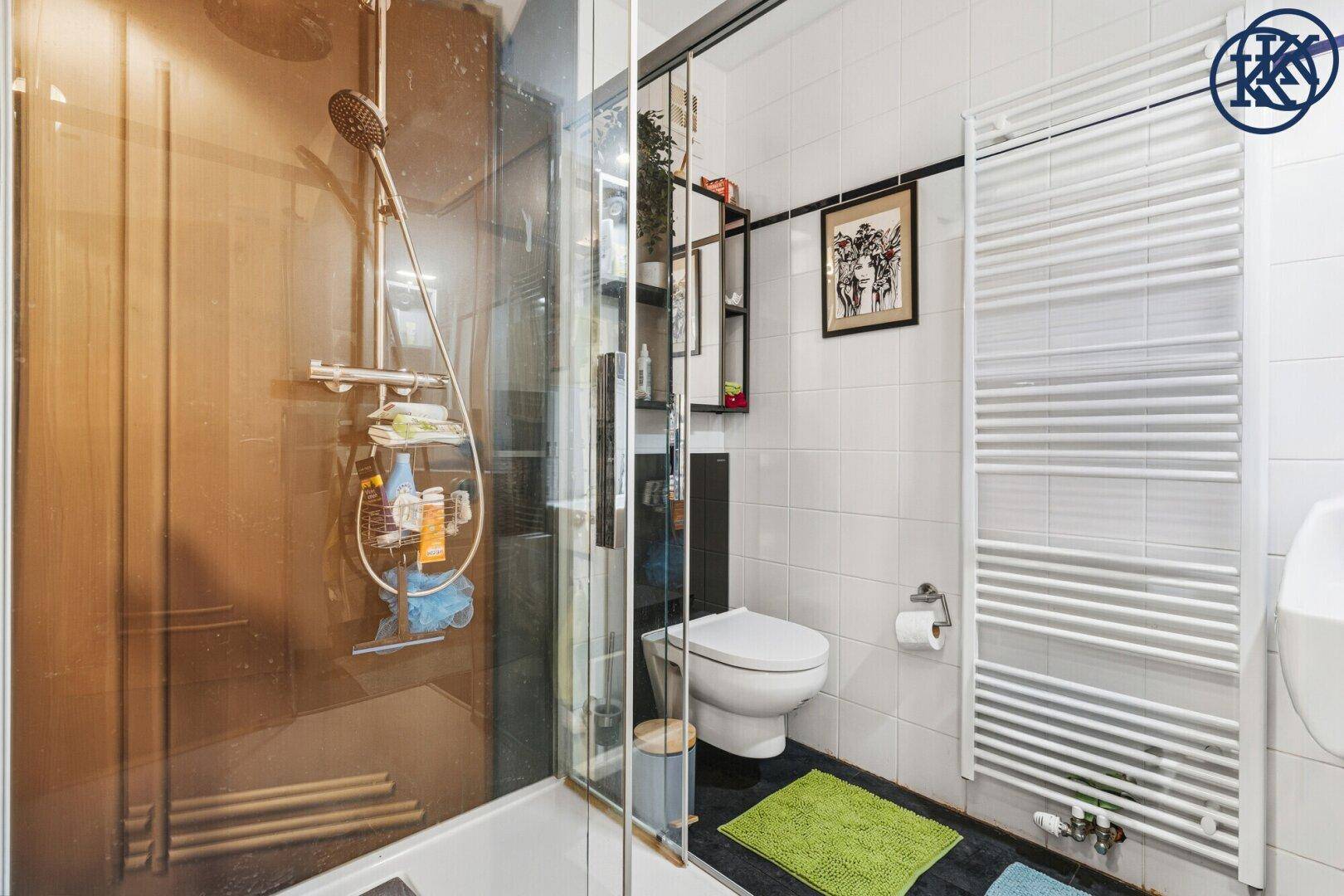Modernes Badezimmer mit Duschkabine, WC und praktischem beheiztem Handtuchhalter.