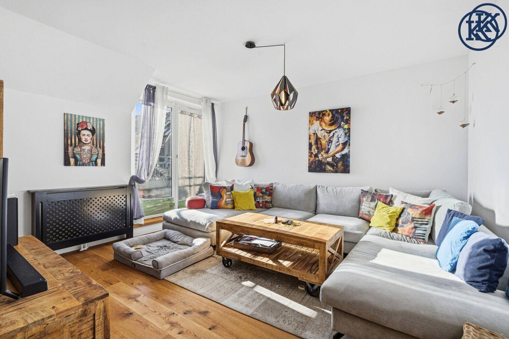 Gemütliches Wohnzimmer mit großem Ecksofa, Holztisch und Zugang zu einem Balkon.