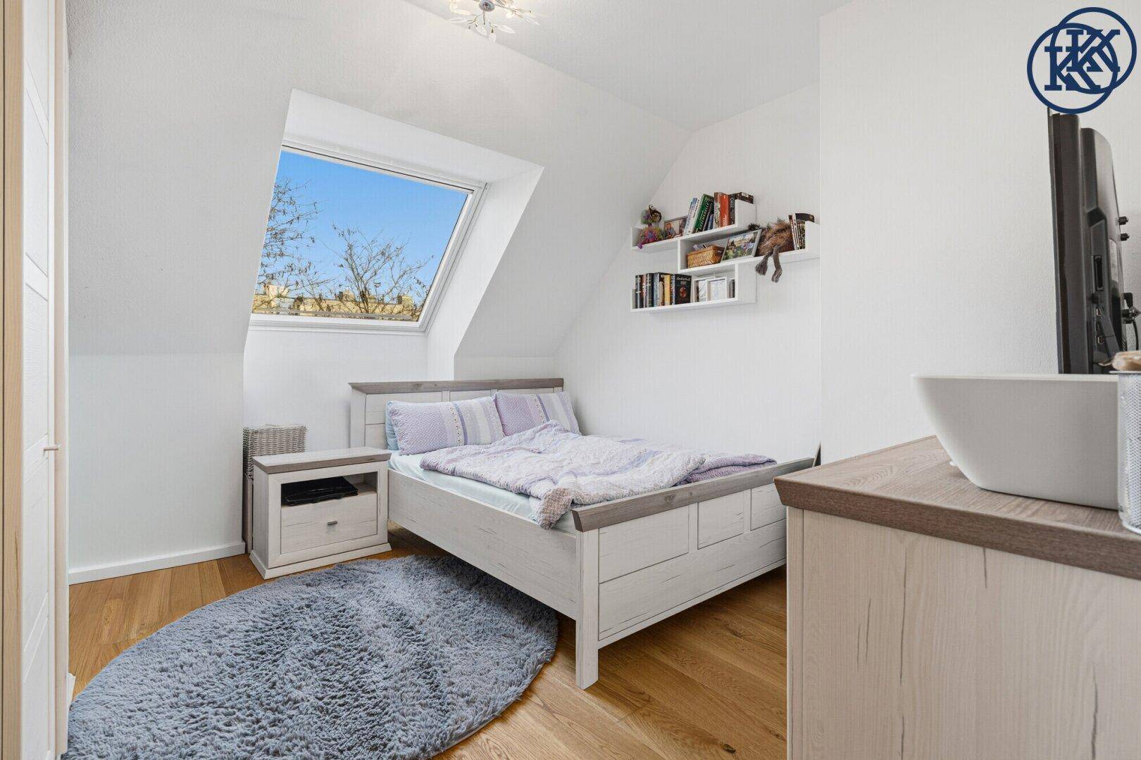 Gemütliches Schlafzimmer mit Dachschräge, Holzboden und großem Dachfenster für viel Licht.
