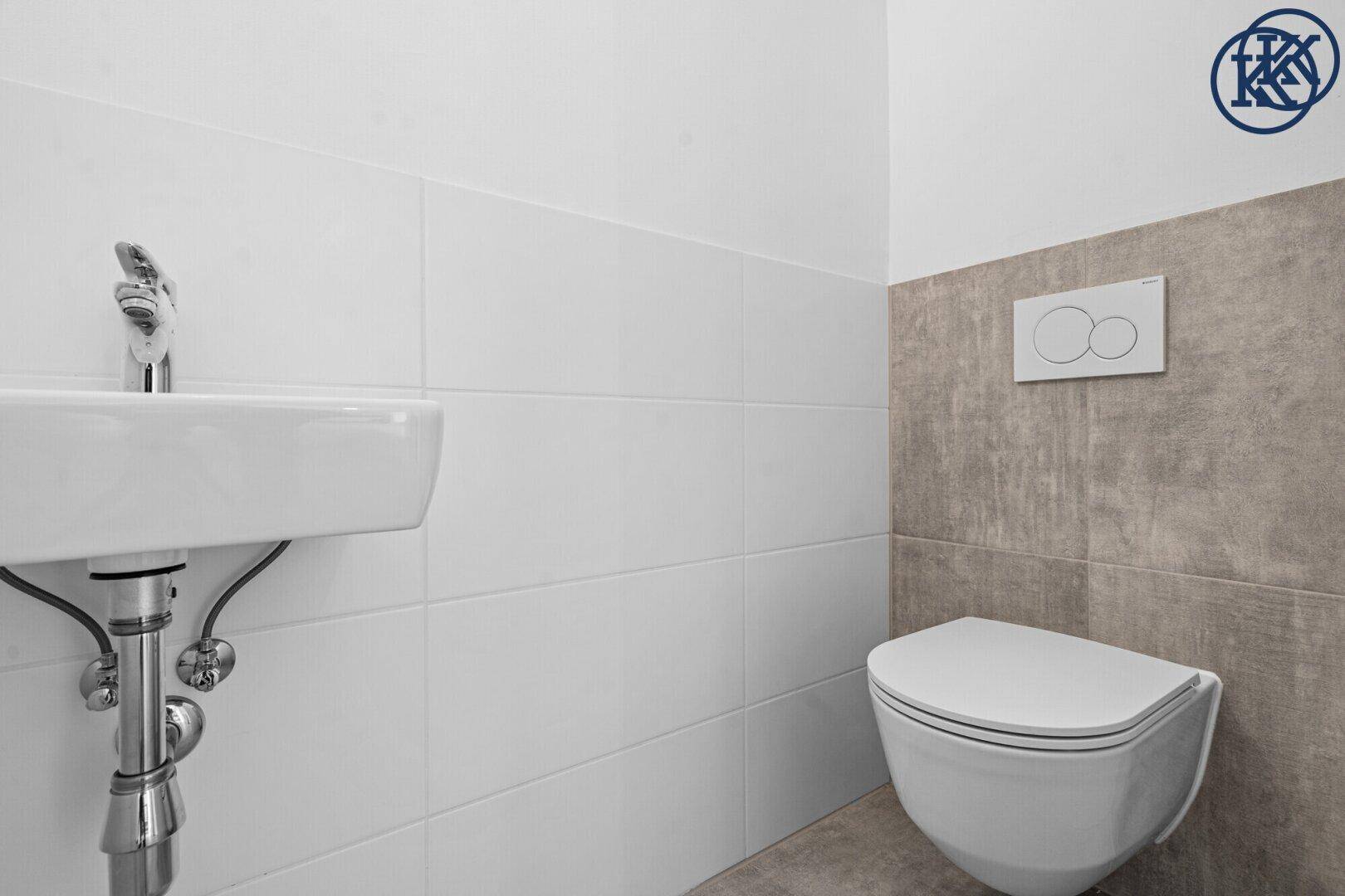 Modernes Gäste-WC mit wandhängendem WC, kleinem Waschbecken und weißen sowie grauen Fliesen.