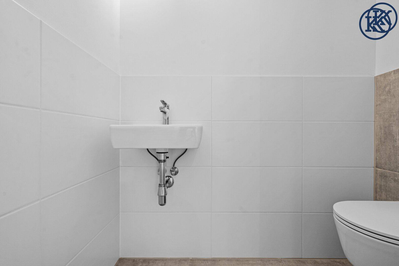 Helles Gäste-WC mit kleinem Waschbecken und weißen Wandfliesen, modern und funktional.