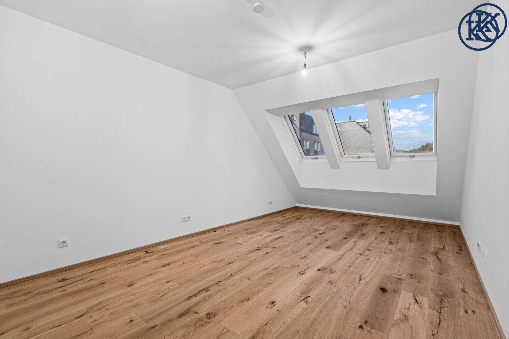 Geräumiges Schlafzimmer mit Holzboden, Dachschrägen und drei Dachfenstern, bietet viel Tageslicht.